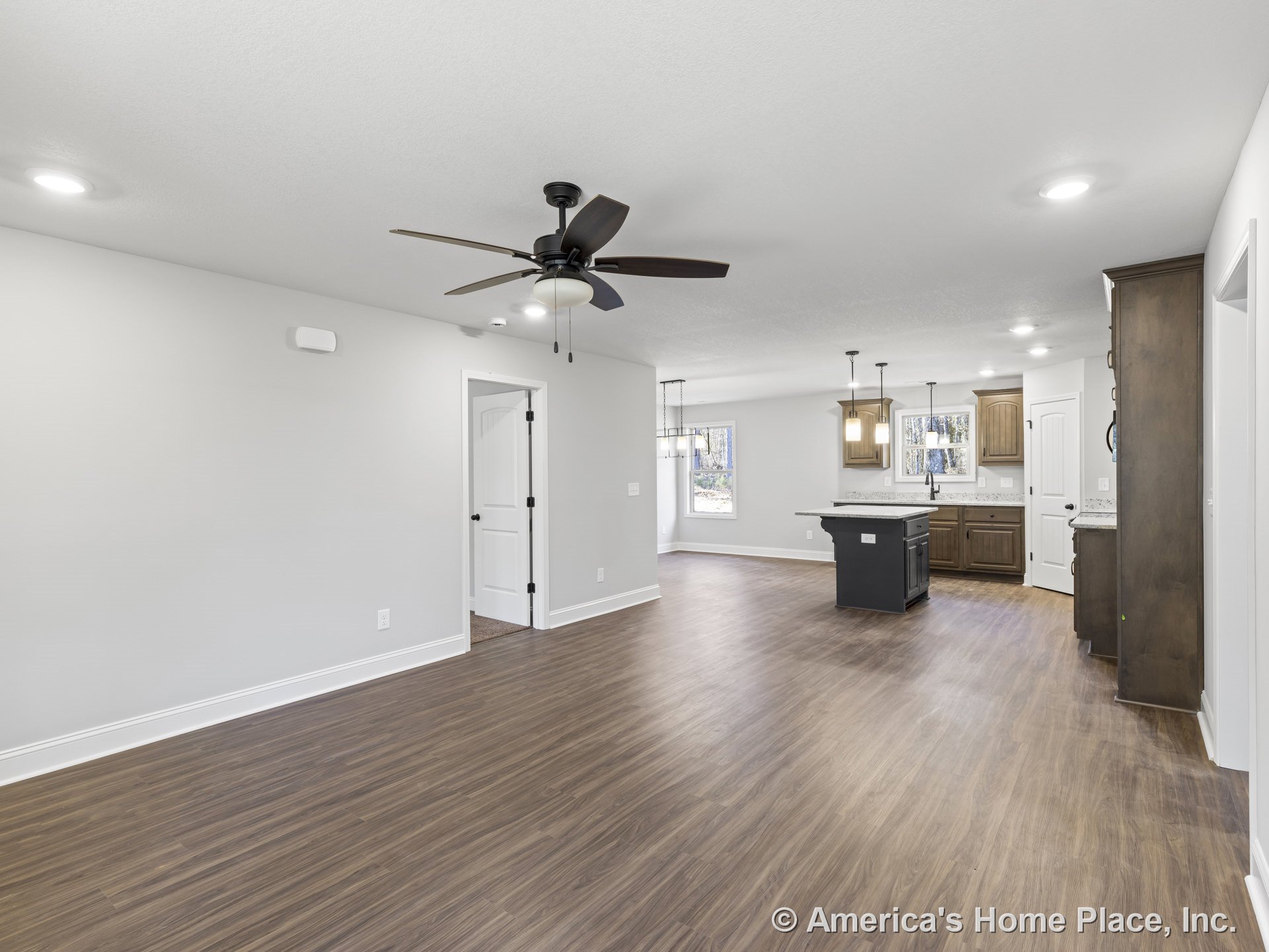 Open-concept living area with wood-look plank flooring, granite kitchen countertops, dark wood cabinetry, pendant and recessed lighting, ceiling fan with light, white trim