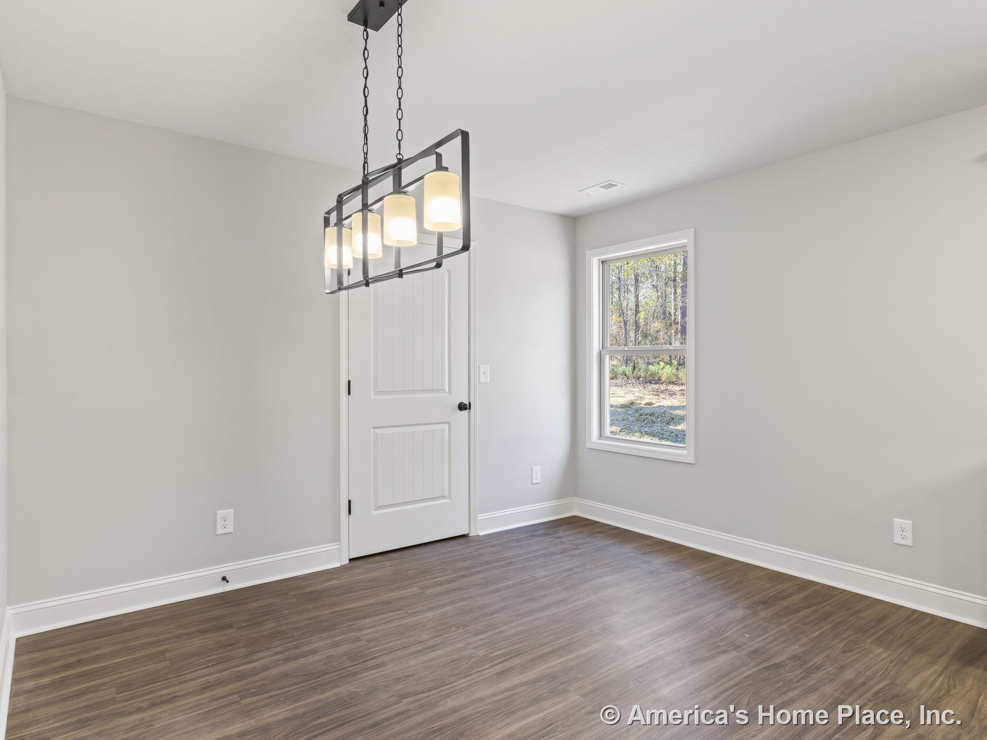 Dining area with modern rectangular chandelier, wood-look flooring, single window framed in white trim, paneled interior door, neutral wall color, and baseboard molding.