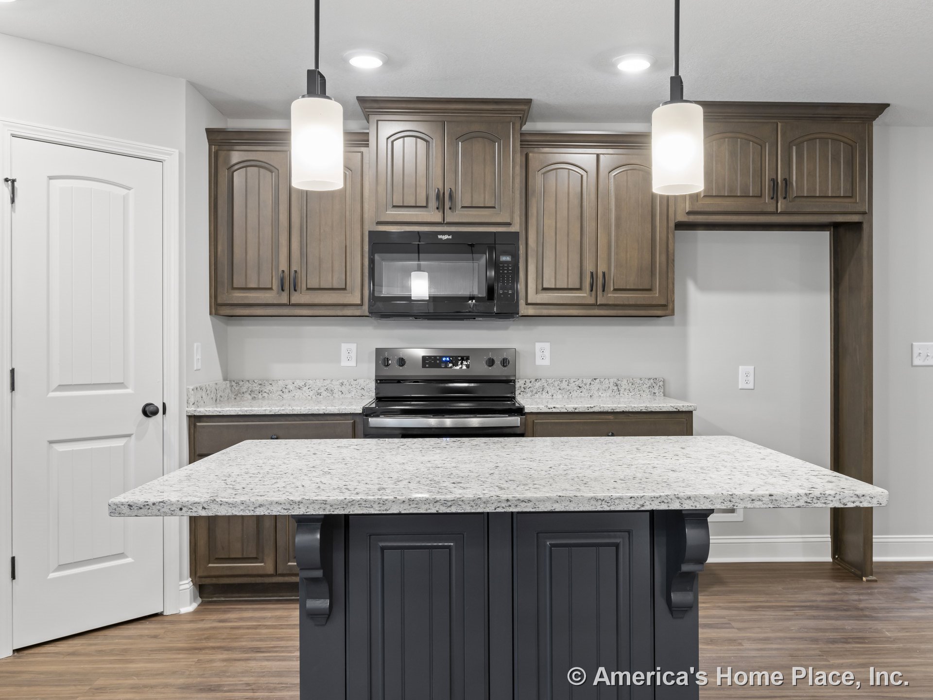 Granite kitchen island with wood cabinetry, built-in microwave, electric range, pendant lights, and wood-look flooring.