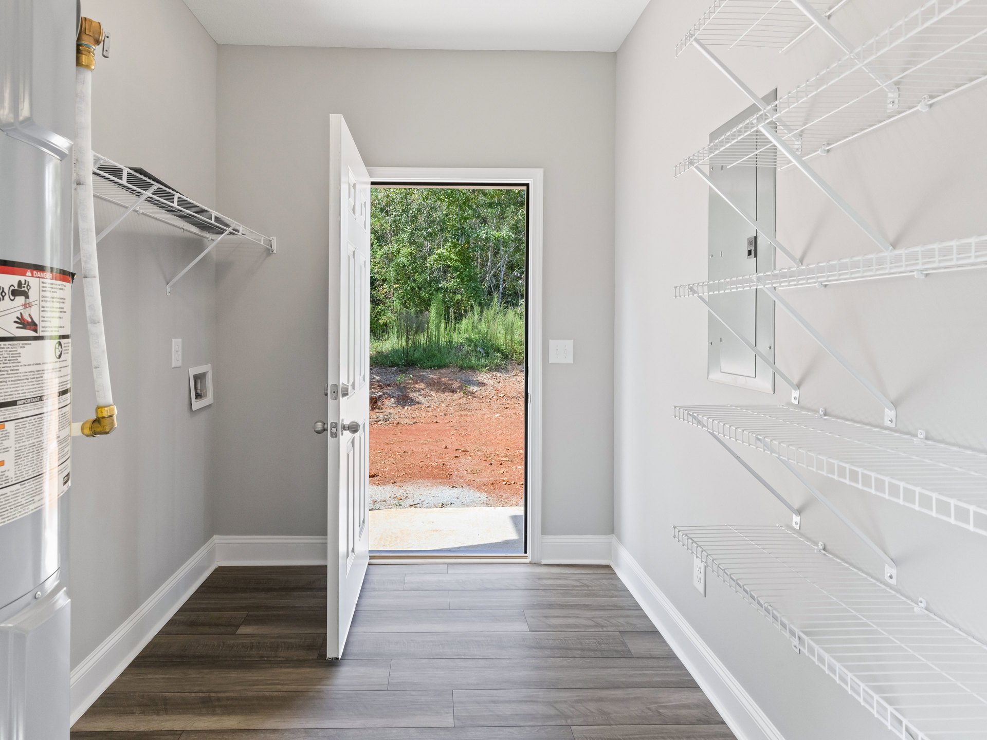 White door opening to a room with built-in shelves, light-colored walls, and wood flooring