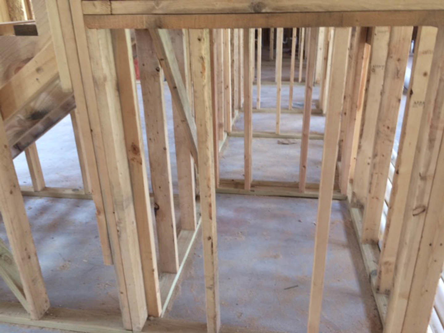 Exposed wood framing and beams inside an unfinished room with plywood flooring and building insulation