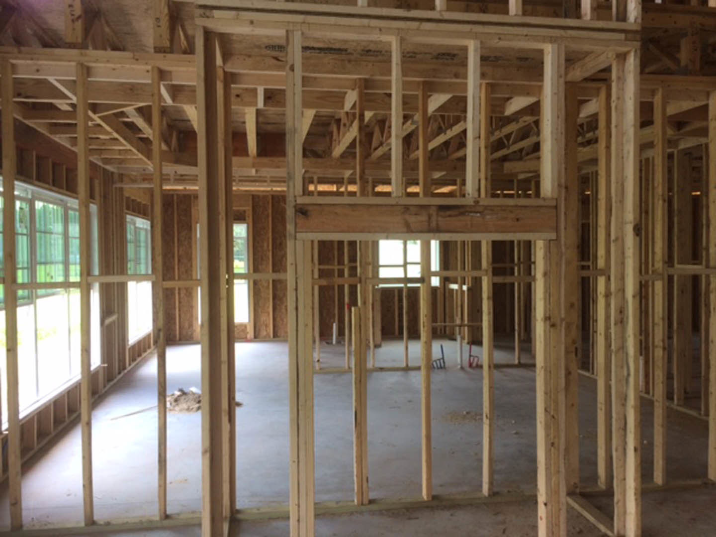Exposed wood framing and beams inside an unfinished residential room with plywood flooring