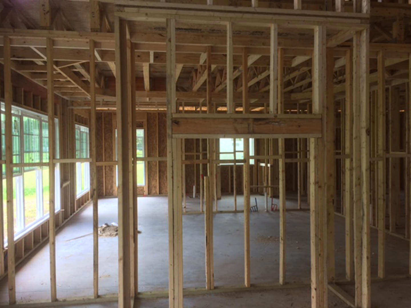 Room featuring a large window set in a wall of vertical wood planks, exposed wooden beams overhead, and hardwood flooring