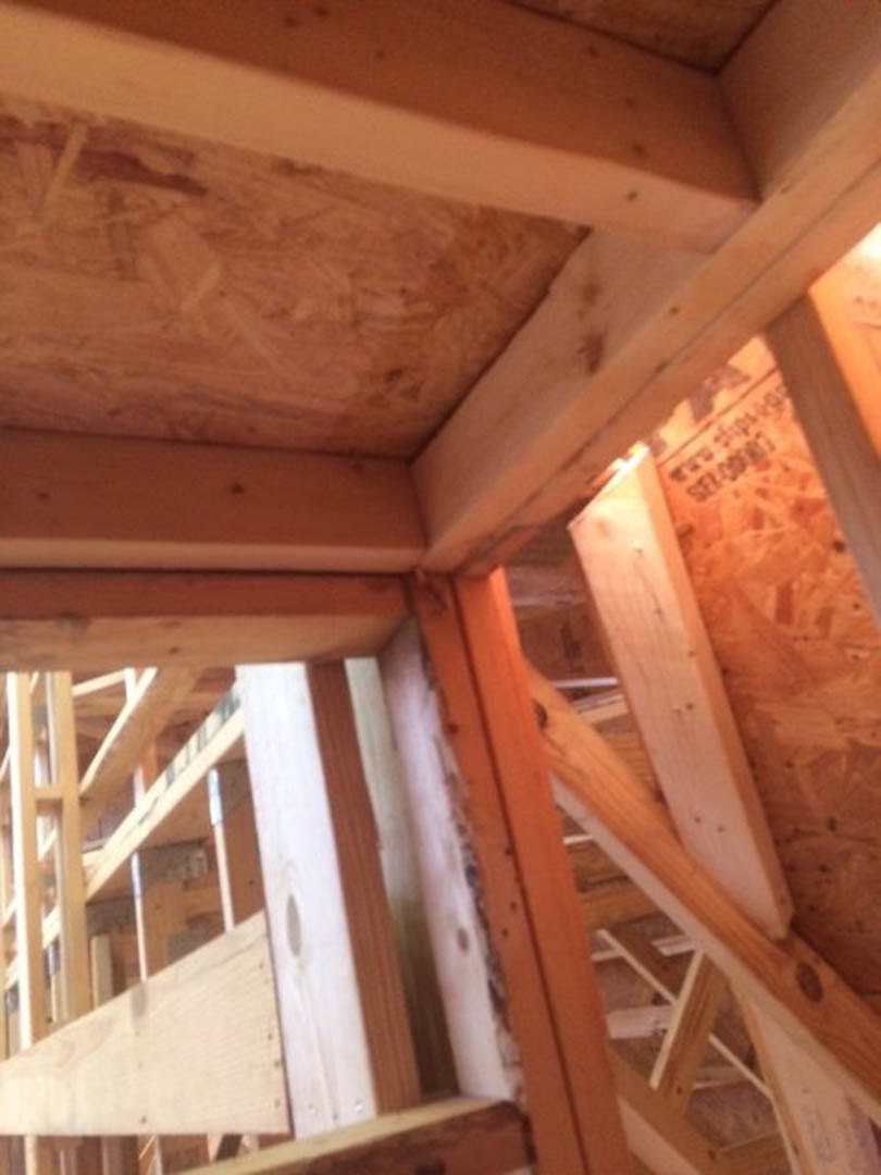 Exposed wooden framing with plywood panels and insulation in an unfinished attic space