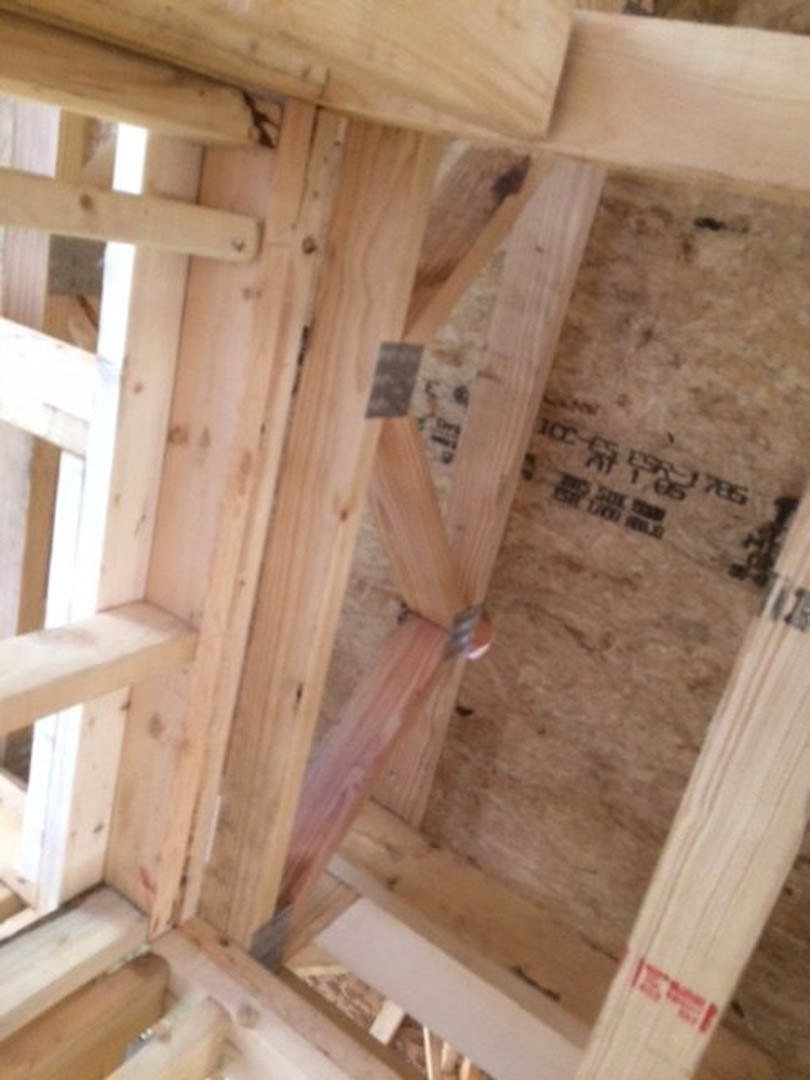 Exposed wooden framing with metal ties and plywood sheathing in a residential construction interior