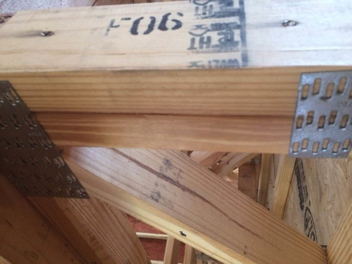 Exposed wooden beams with metal brackets and visible grain, close-up showing dark marks and textured wood finish