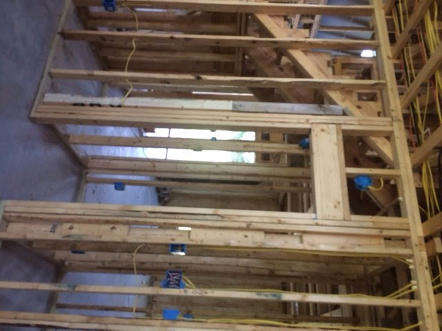 Exposed wood framing with beams, planks, and steel supports inside a partially constructed residential home