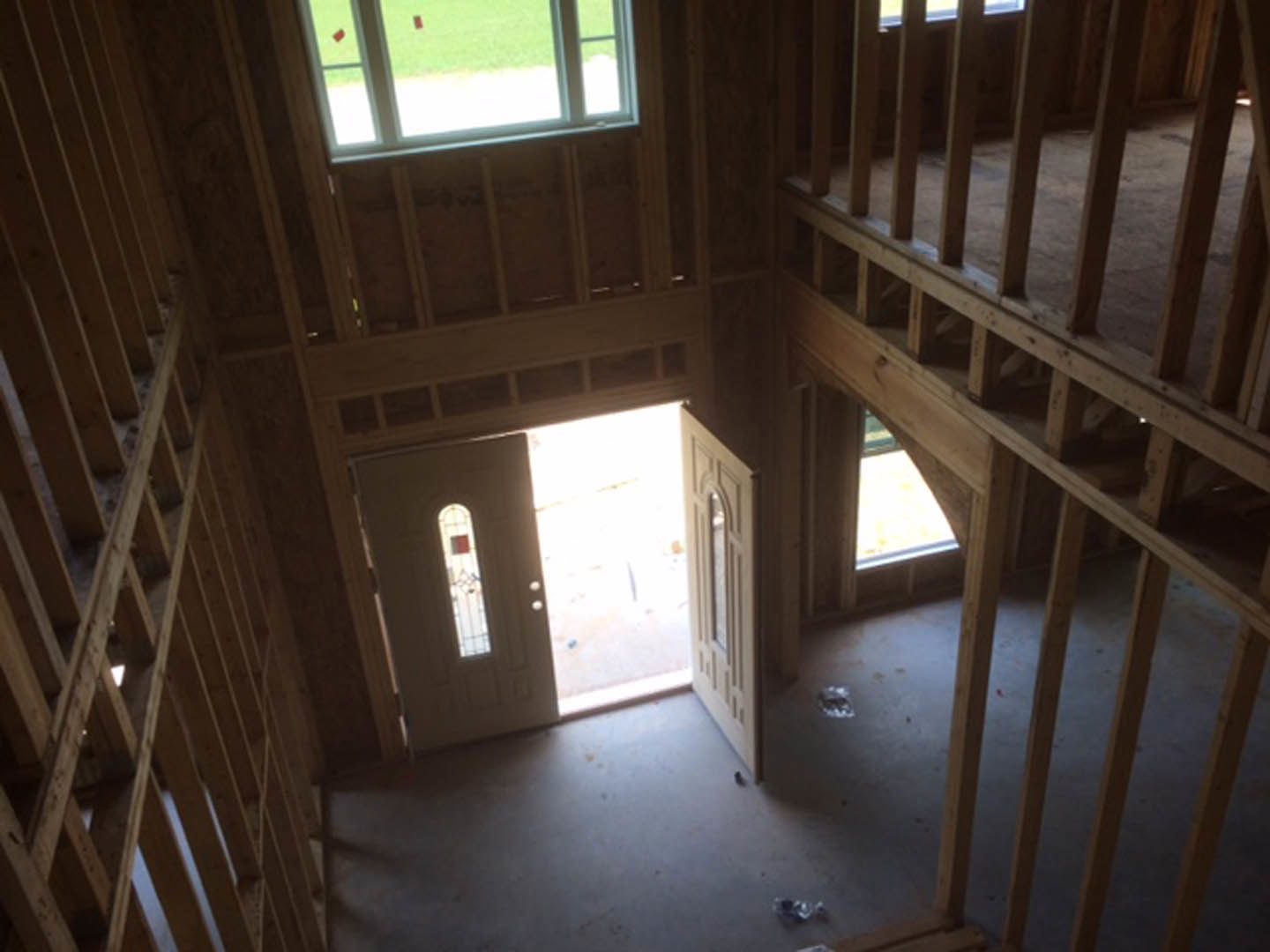 White door with glass window, exposed wooden ceiling beams, light-colored walls, and large windows allowing natural daylight into the room.