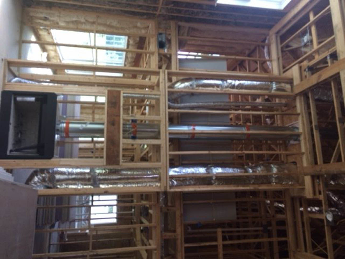 Wood framing with exposed plumbing pipes and a window, unfinished interior construction with visible lumber beams