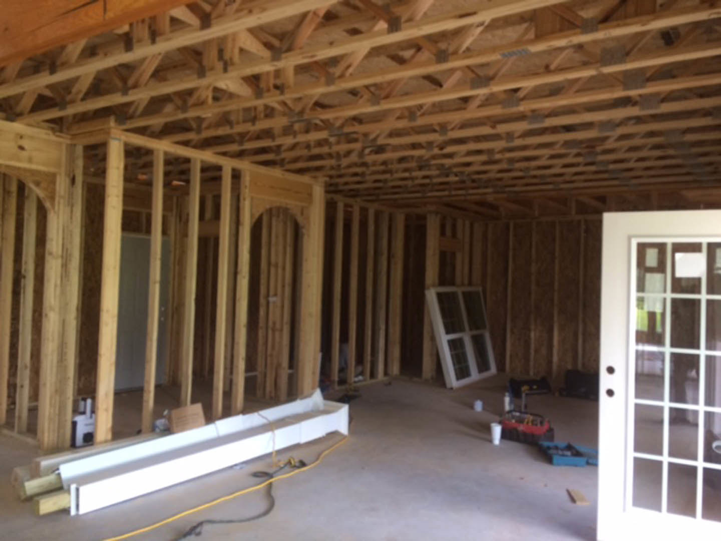 Wood-framed room featuring exposed ceiling beams, hardwood plank walls, a white-framed window, and a door with natural wood finish