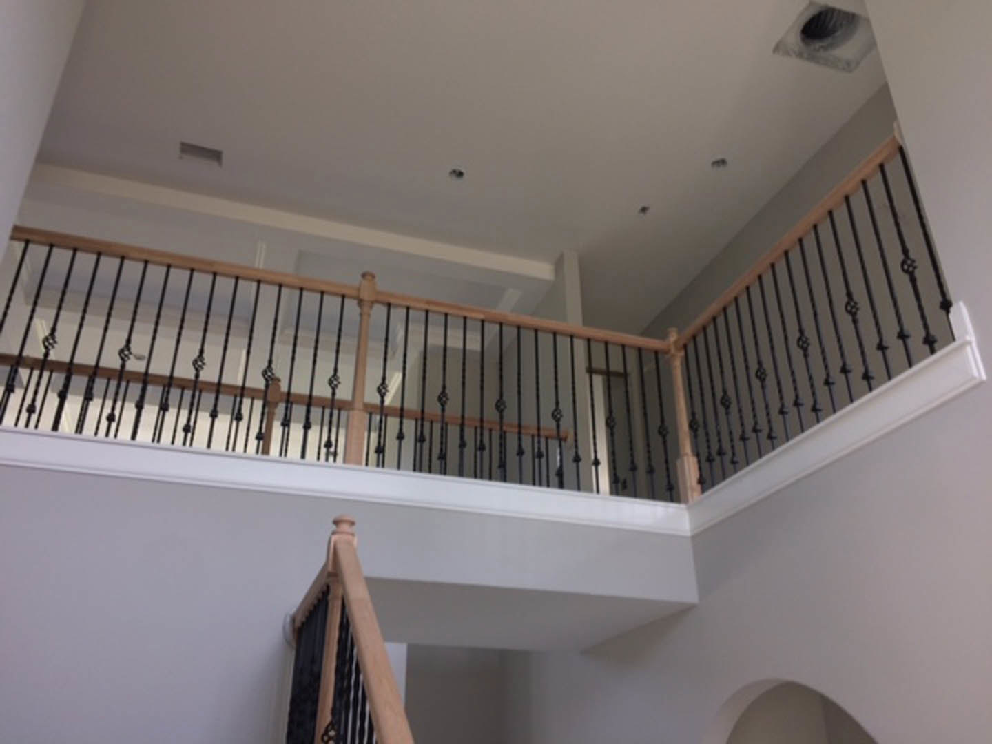 Wood staircase with matching railing, white plaster walls, crown molding, and ceiling detail in a residential interior