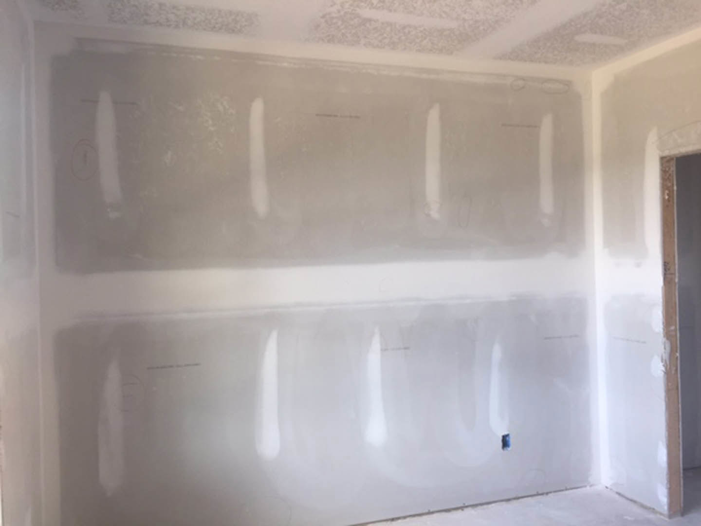 Bathroom with white plaster walls, white ceiling, and painted surfaces, featuring a shower area and minimal black markings on the wall.