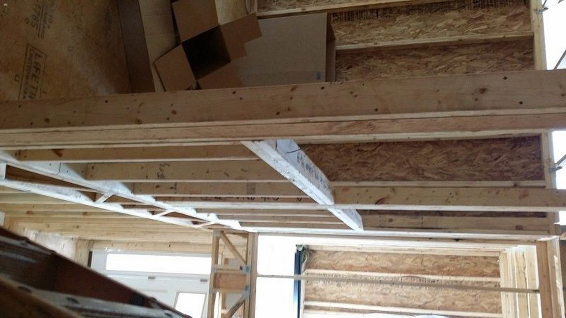 Exposed wood framing with vertical beams, horizontal planks, and unfinished walls inside a residential construction site