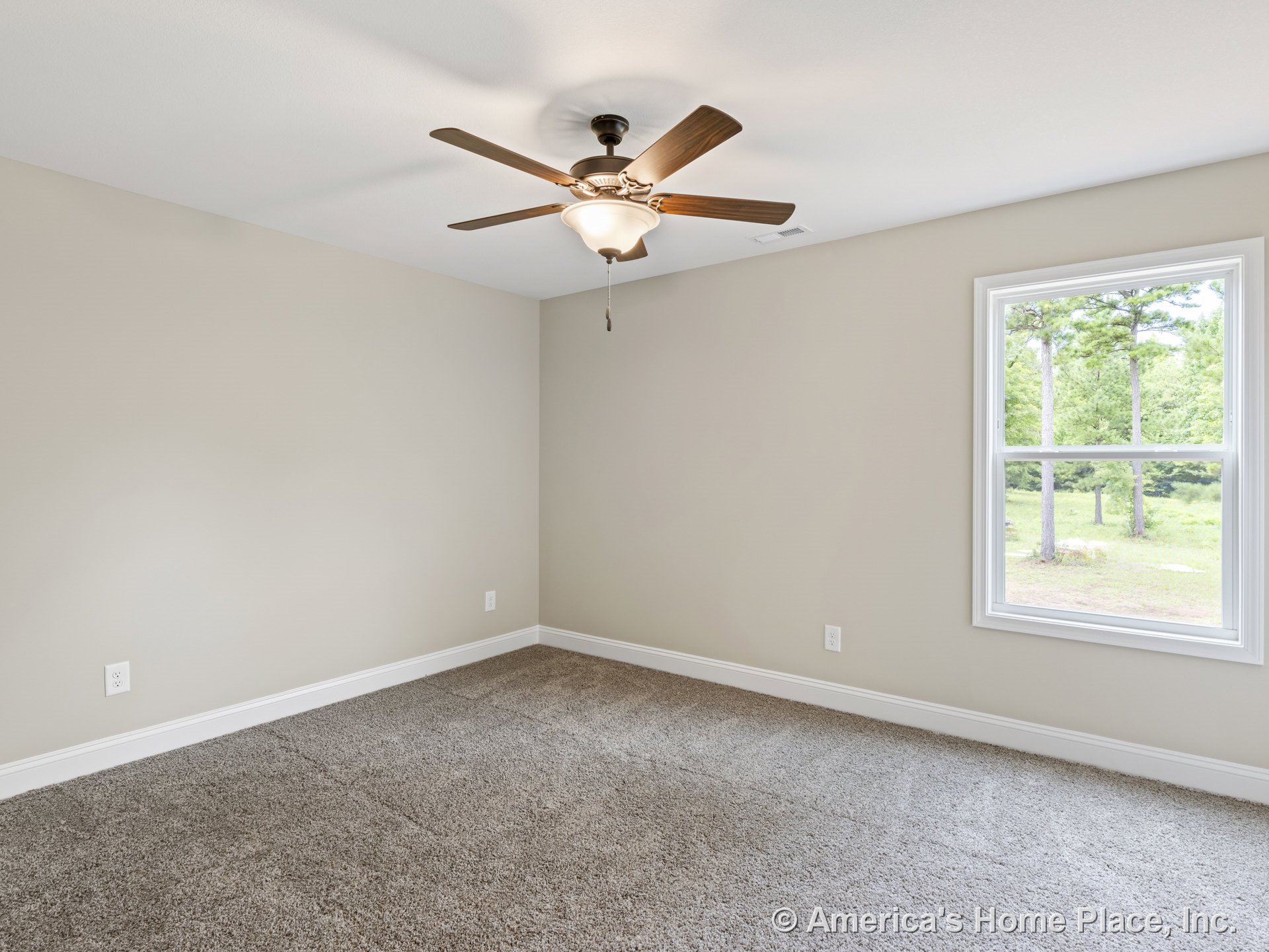 Beige carpet flooring, neutral walls, white baseboards, ceiling fan with light fixture, large single window with white trim allowing natural light