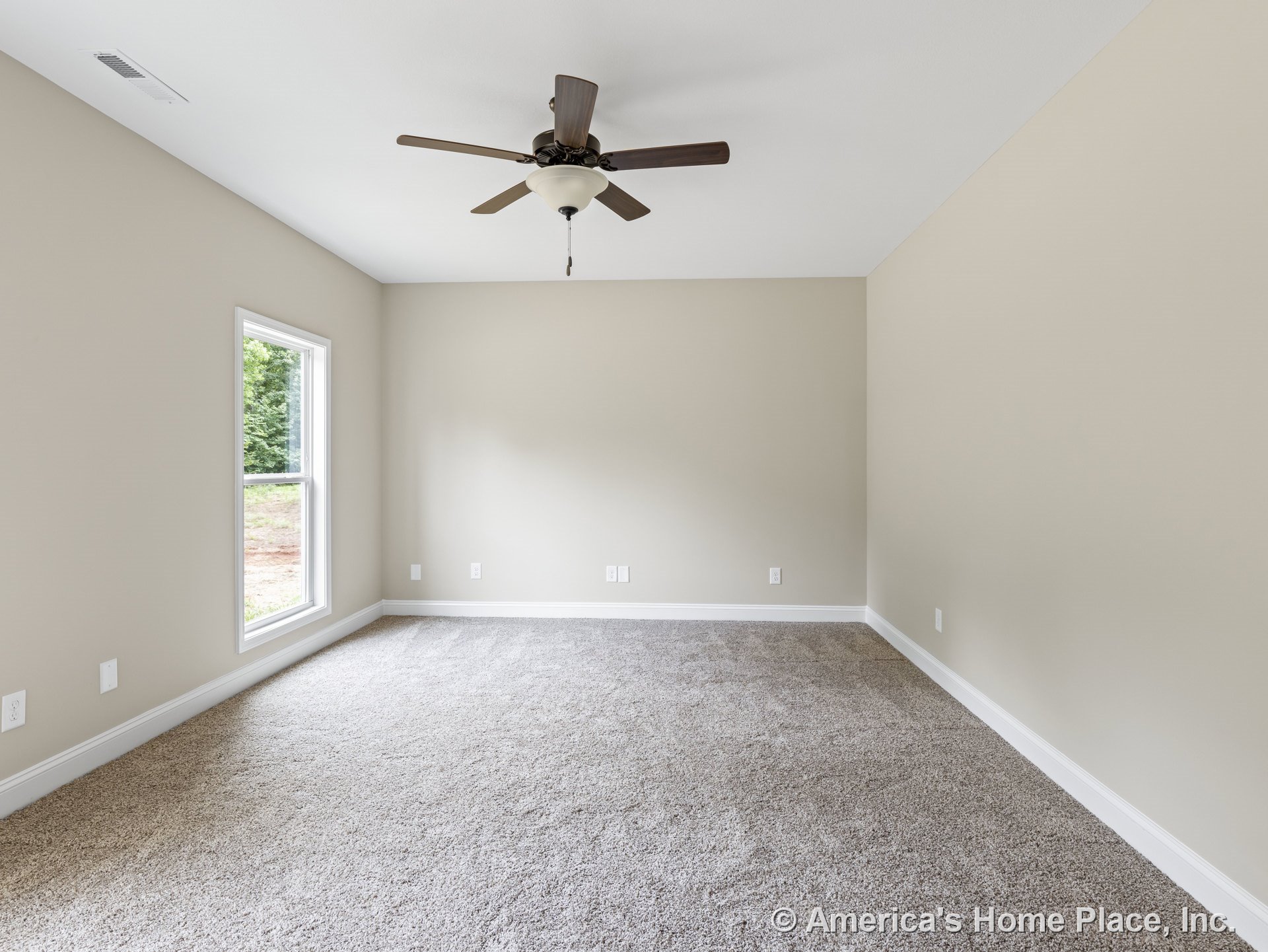 Carpeted bedroom with neutral wall paint, white baseboards, single large window with white trim, ceiling fan and light fixture, wall outlets, and abundant natural light.