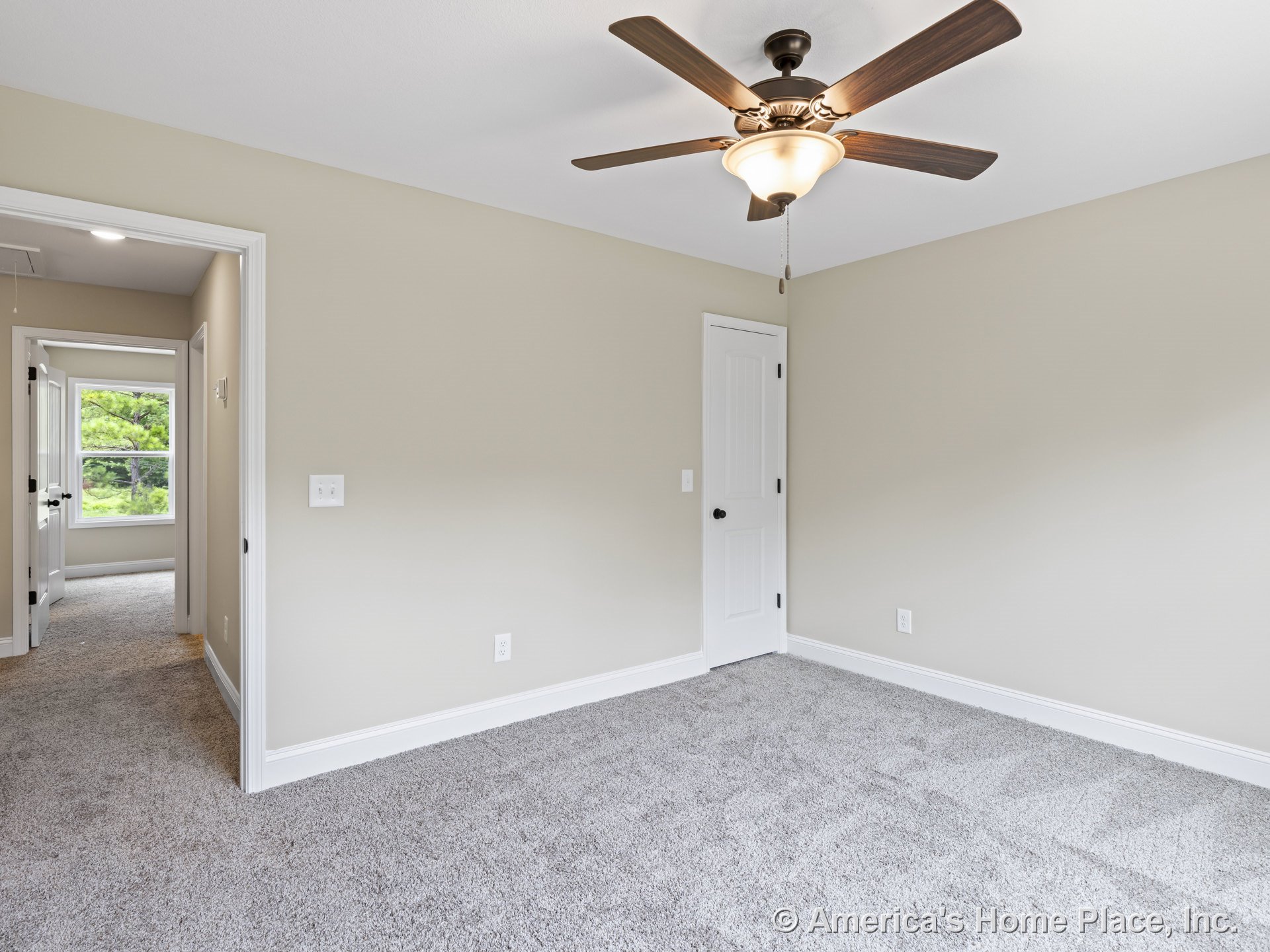Bedroom with carpet flooring, neutral wall paint, white trim and baseboards, ceiling fan with integrated light, paneled interior doors, and a large window visible in the adjacent