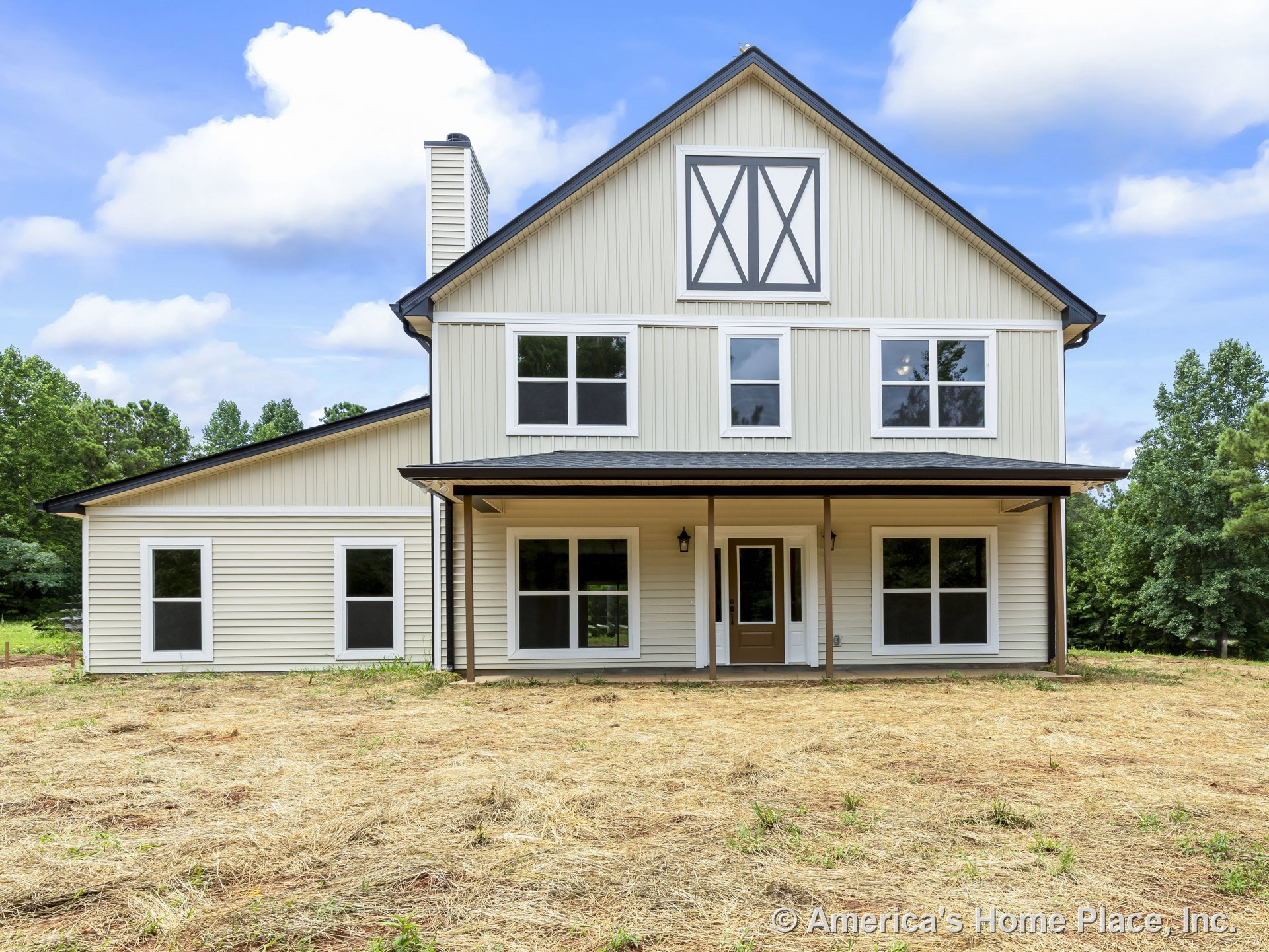 Two-story farmhouse-style exterior with vertical siding, gable roof, covered front porch, double front door, multiple large windows, prominent chimney, decorative trim, and