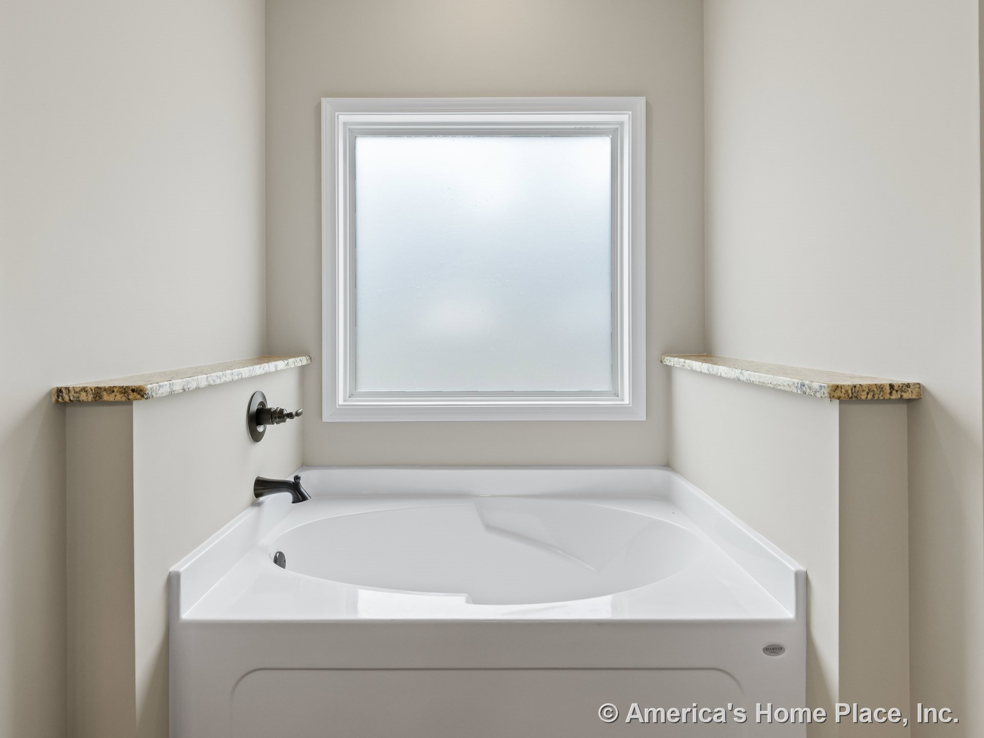 Built-in white soaking tub set beneath a frosted glass window with granite ledges, neutral wall color, chrome tub faucet, and detailed window trim.