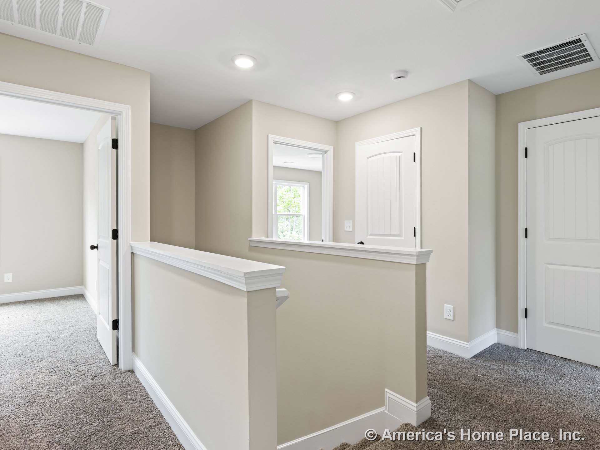 Upstairs hallway with carpet flooring, recessed ceiling lights, white paneled doors, neutral painted walls, window with white trim, staircase railing, ceiling vent, and baseboards.