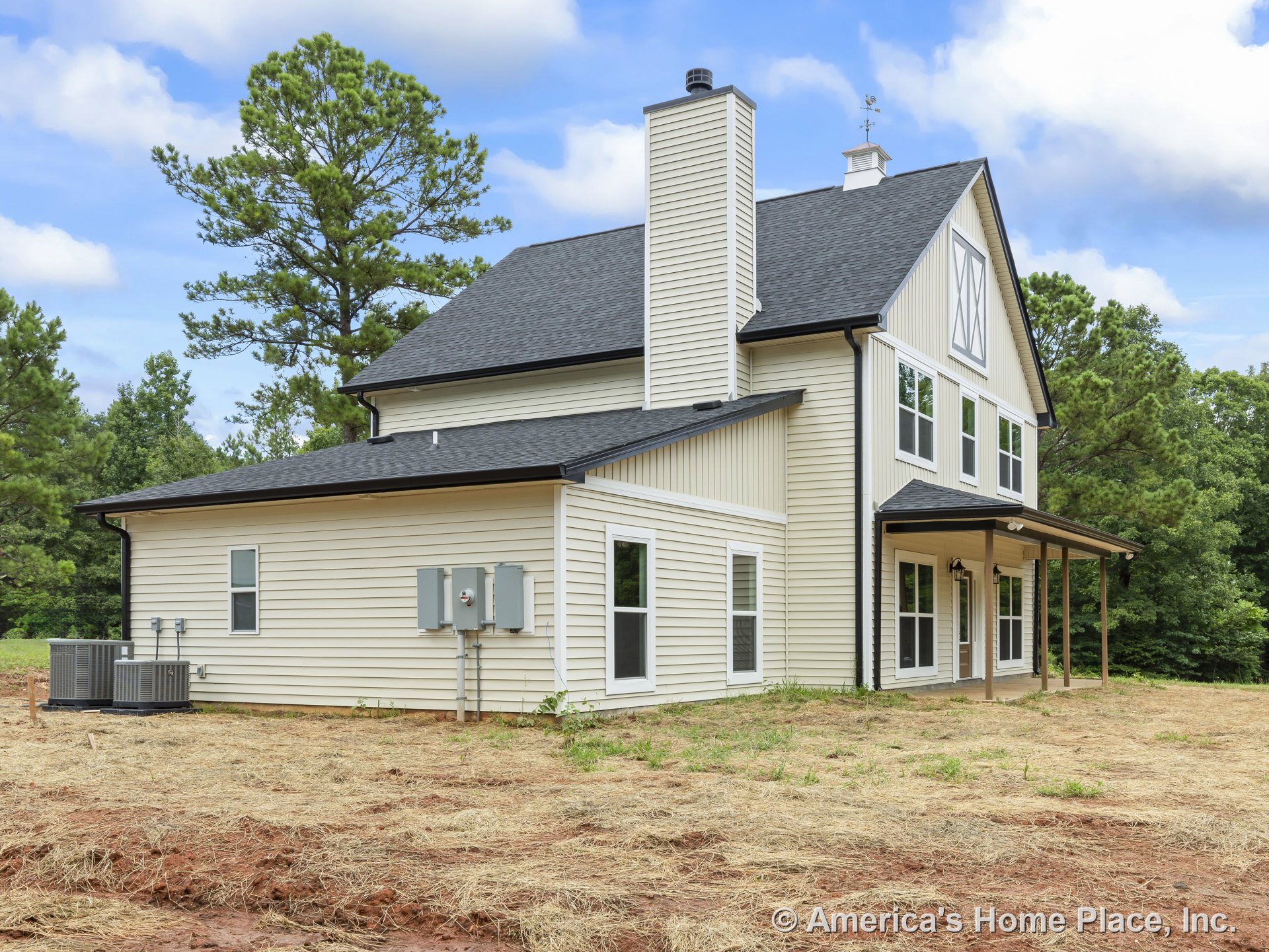 Light-colored vertical and horizontal siding with farmhouse-style trim, covered porch supported by posts, multiple double-hung windows, exterior chimney, dark shingle roof, visible