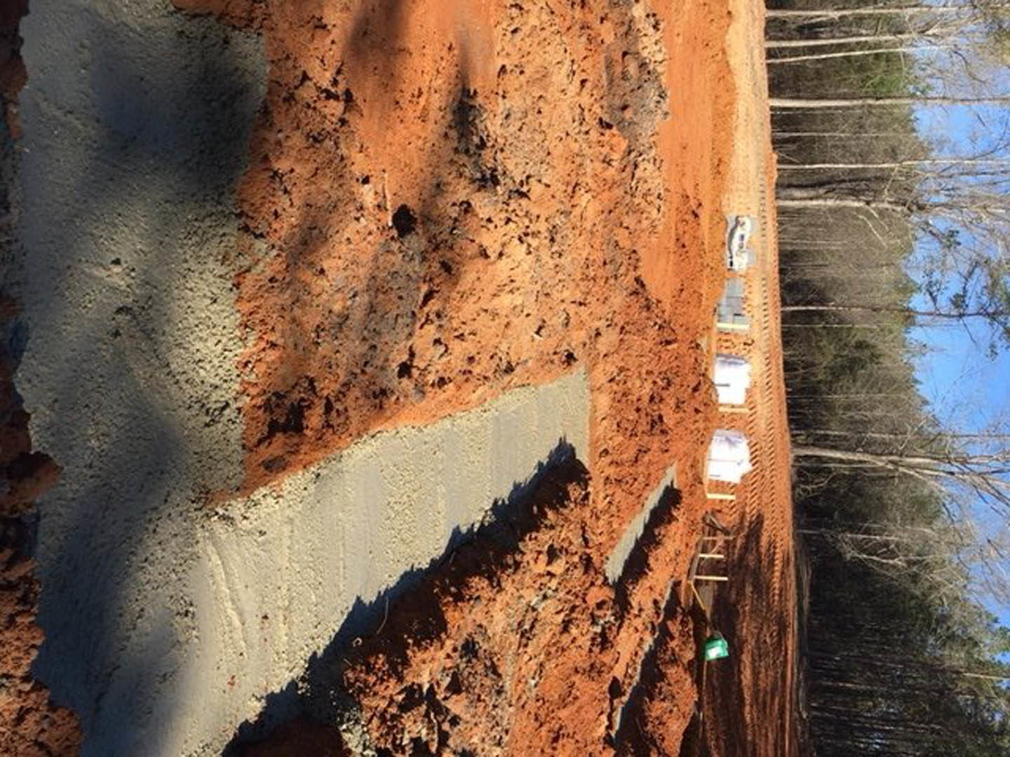 Dirt road with visible footings and patches of soil, surrounded by outdoor landscape in Opelika