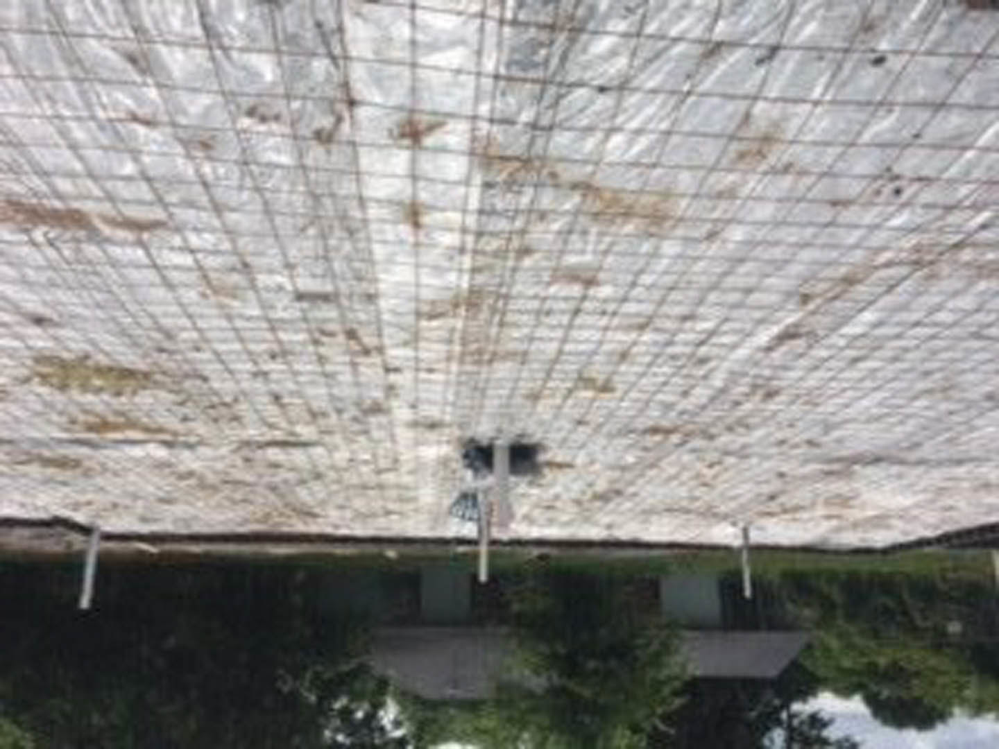 White tarp draped over exterior roof structure, partially obscuring building details