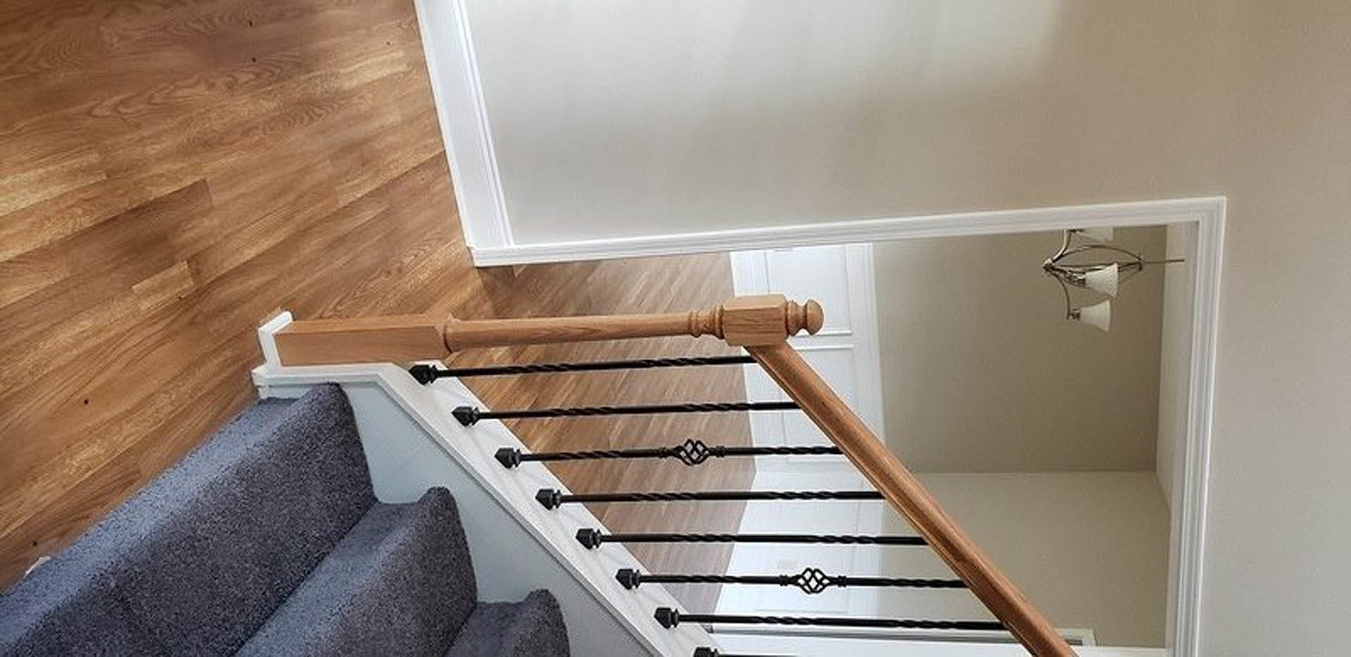 Carpeted staircase with wood handrail, hardwood steps, plaster walls, and plywood accents