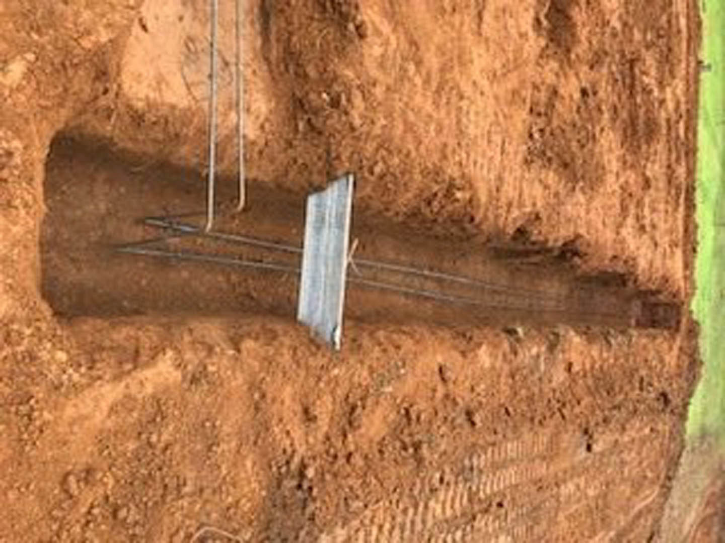 Metal frame embedded in soil surrounded by rocks and dirt outdoors