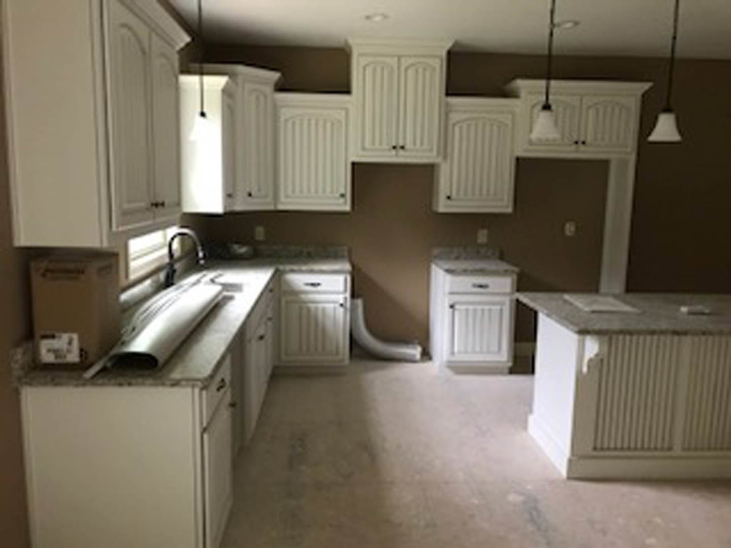 White kitchen with shaker cabinets, stainless steel appliances, light stone countertops, undermount sink, and hardwood flooring