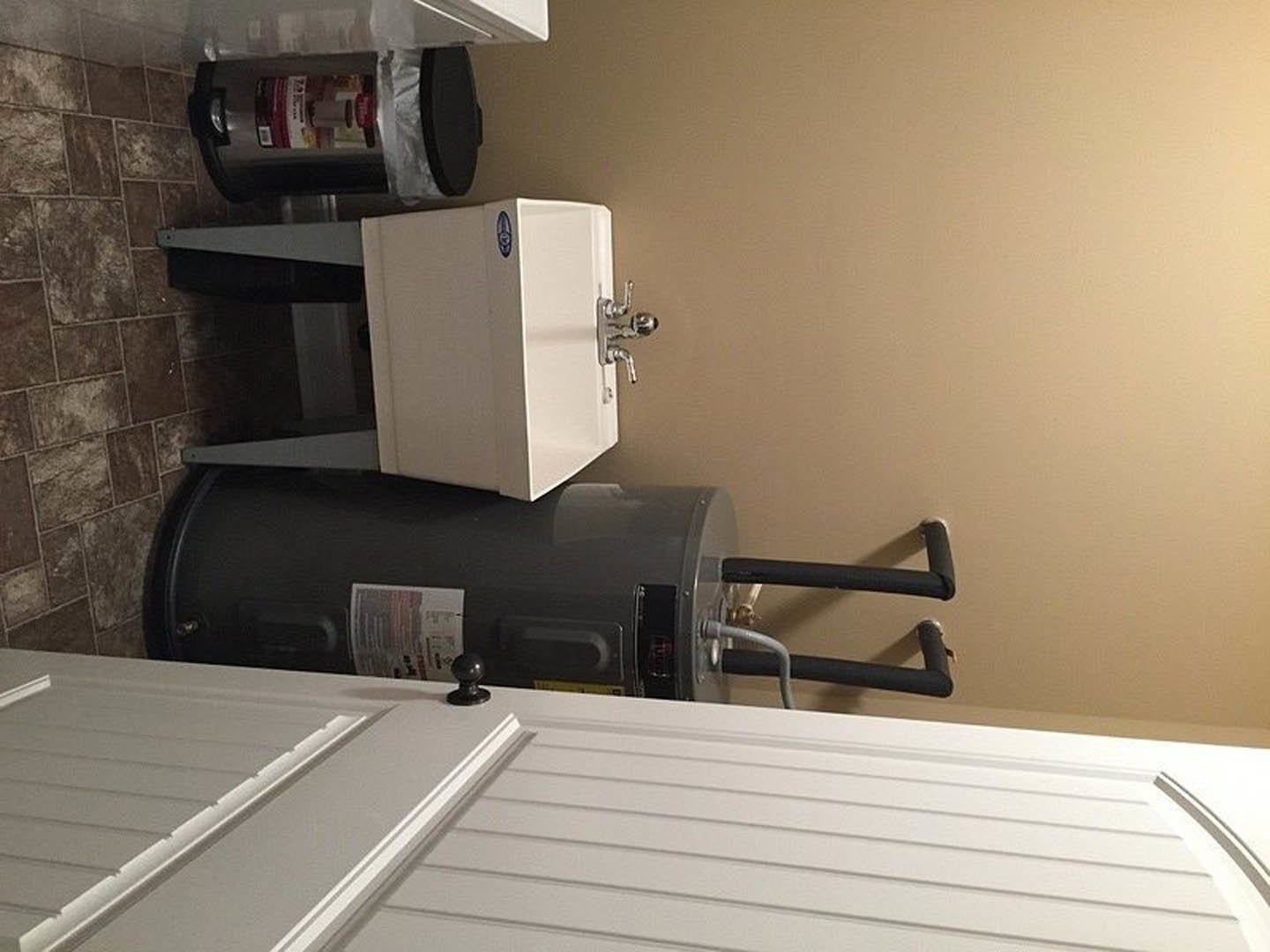 Undermount sink with chrome faucet set in a utility room countertop, white cabinetry, paper and silver bag on surface, white door with black handle in background