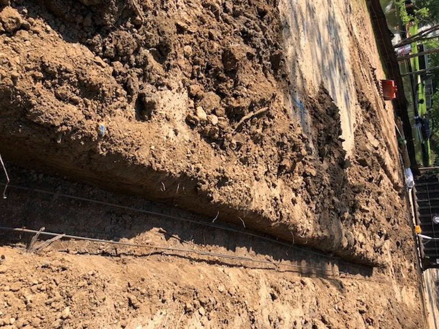 Dirt field with exposed metal wires and rocky soil, outdoor construction site