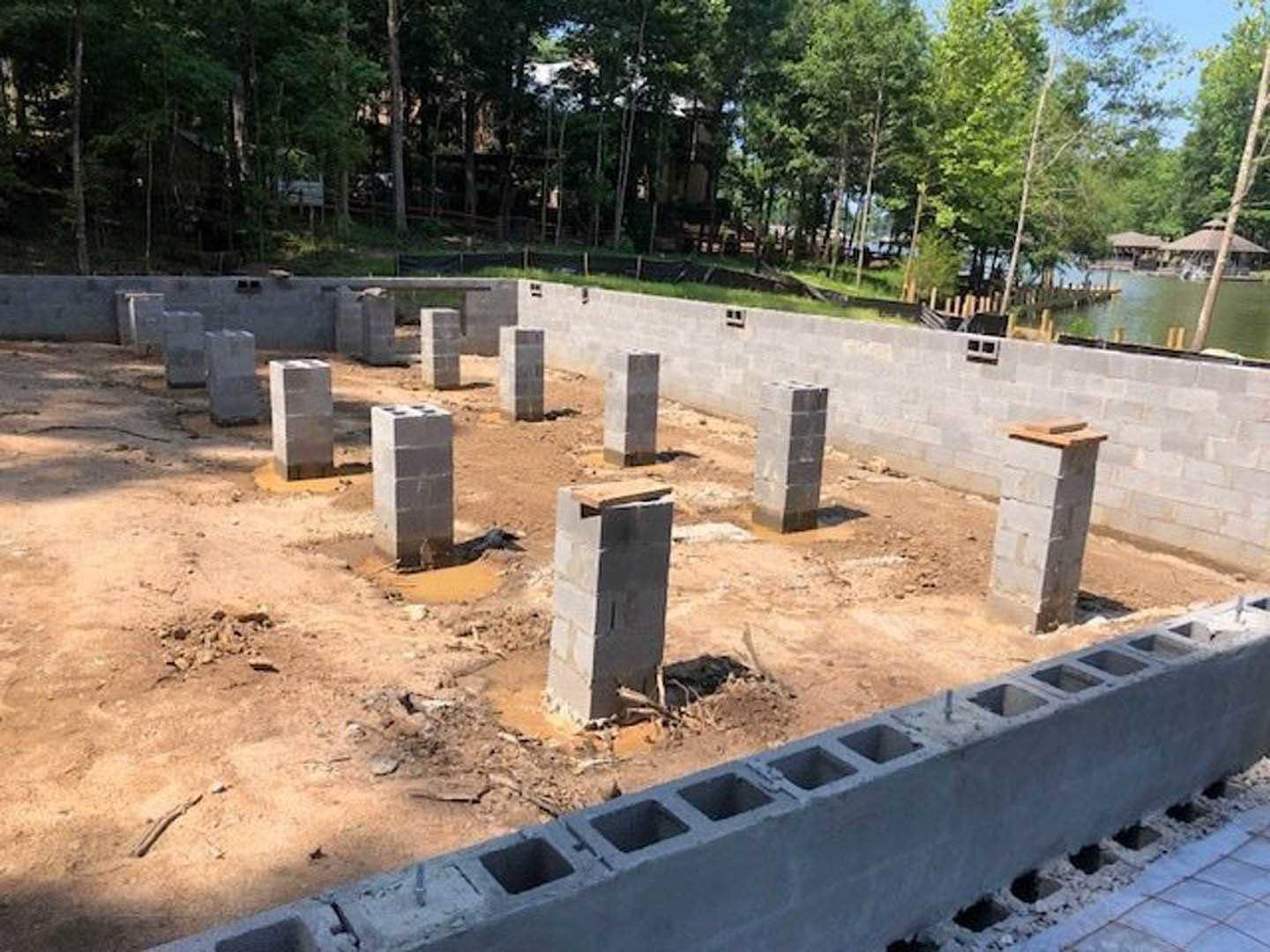 Concrete foundation with multiple block pillars surrounded by trees and bare ground