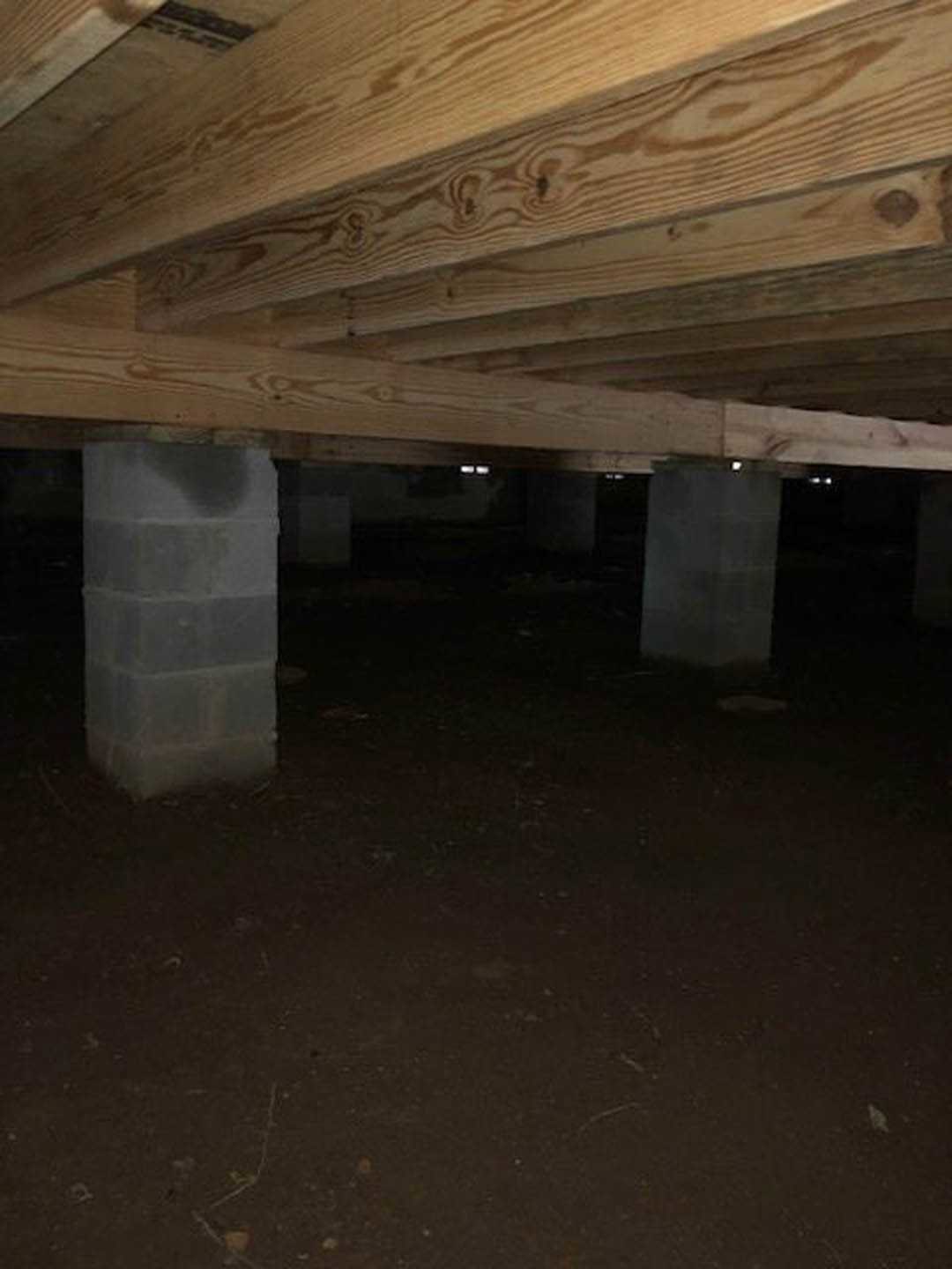 Concrete pillar and wooden ceiling beams in a dimly lit room with dark walls and white accent surfaces