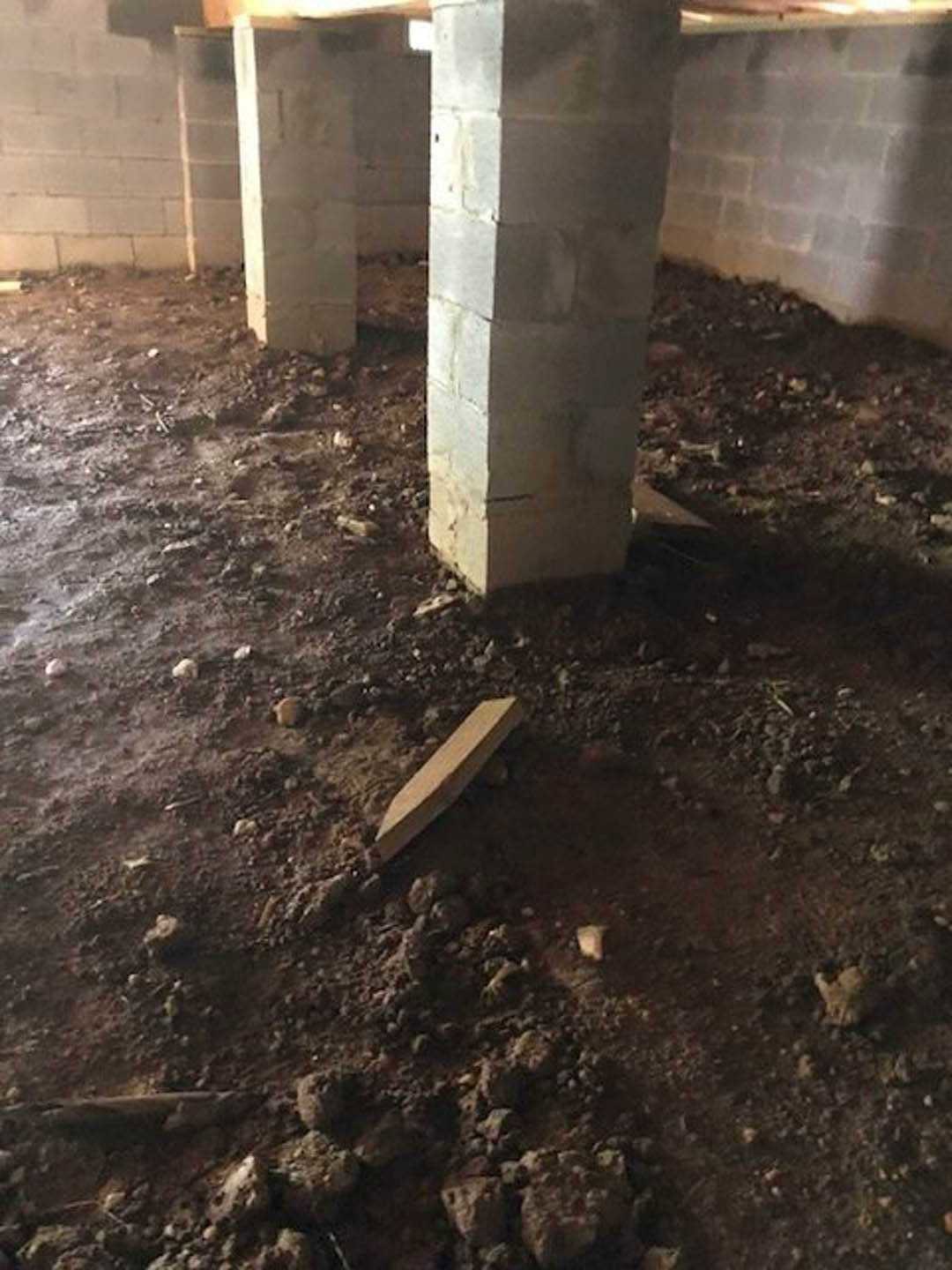 Concrete pillar with smooth finish stands in a spacious room featuring light-colored flooring and neutral walls; wooden object rests nearby on the ground.