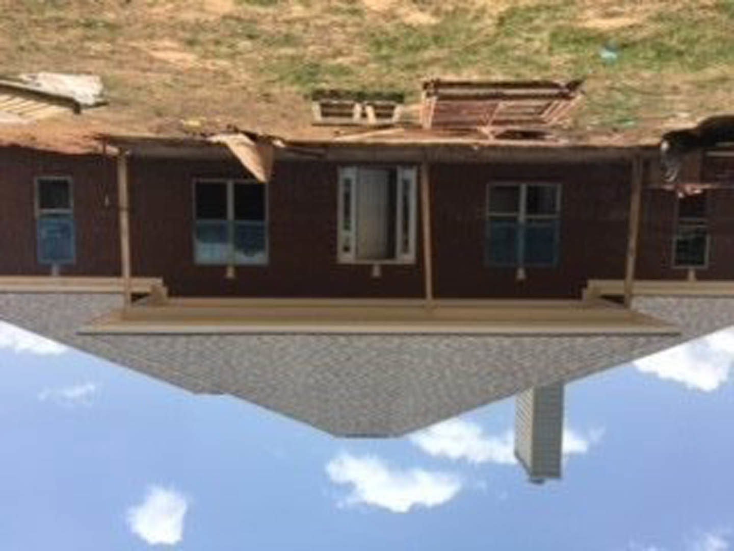 Two-story custom home with gray shingle roof, white trim, multiple pane windows, and light-colored siding under a partly cloudy sky