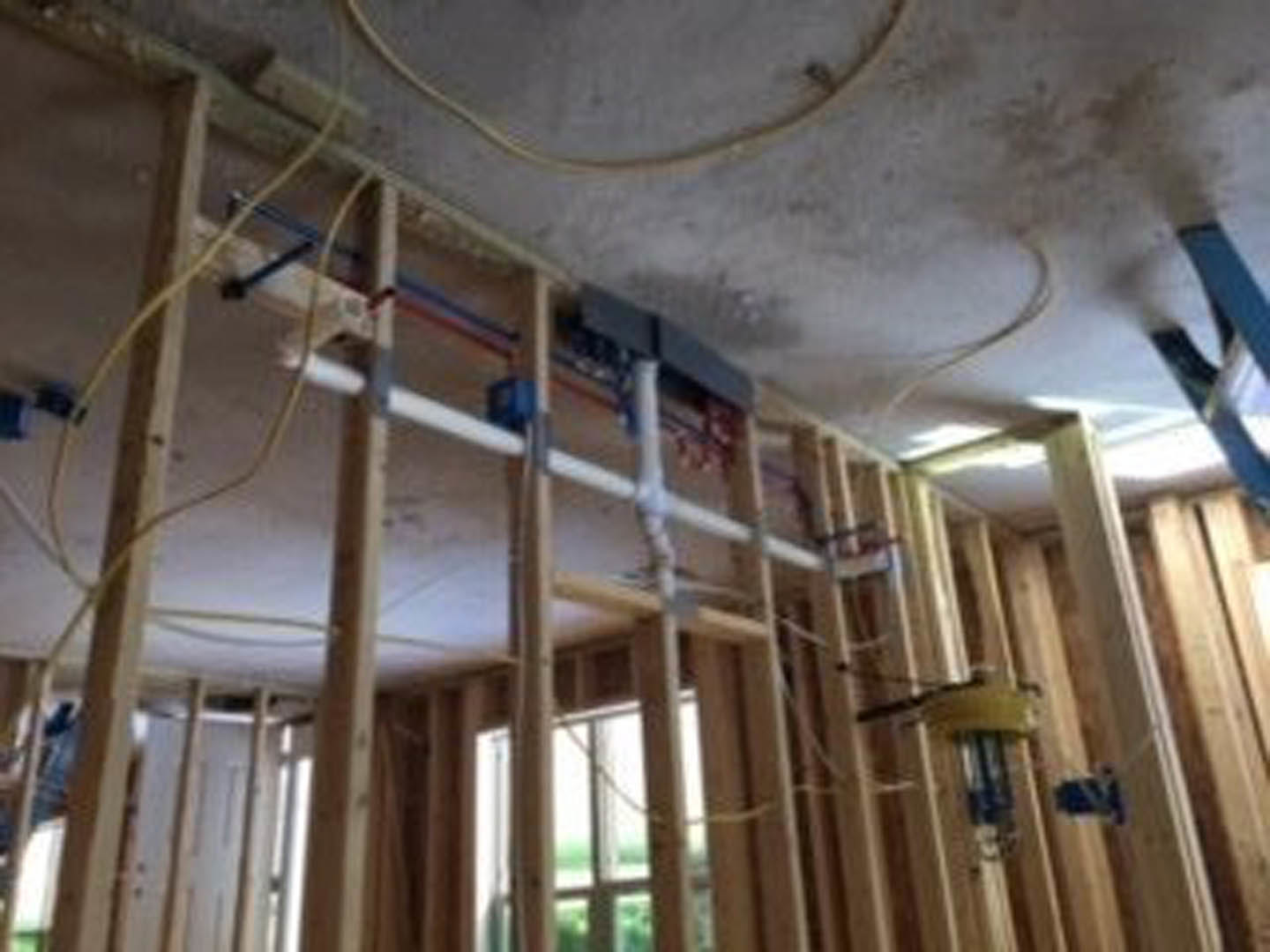 Unfinished interior room with exposed wooden beams, wall insulation, and visible metal pipes along the wall and ceiling