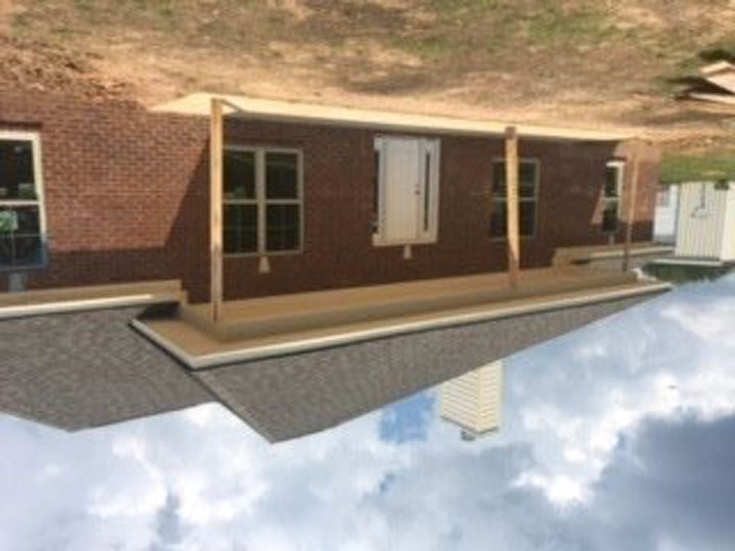 Red brick house with white front door and white-framed window, gabled roof, cloudy sky overhead