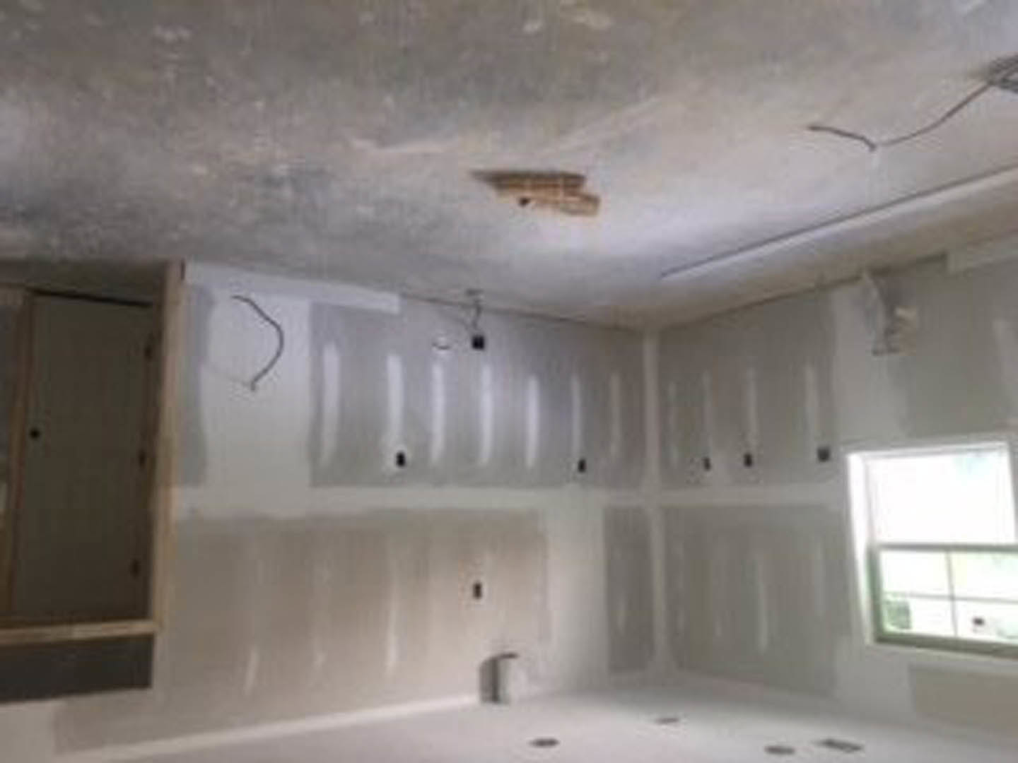 Bathroom with white plaster walls, large window, freestanding bathtub, and light-colored flooring