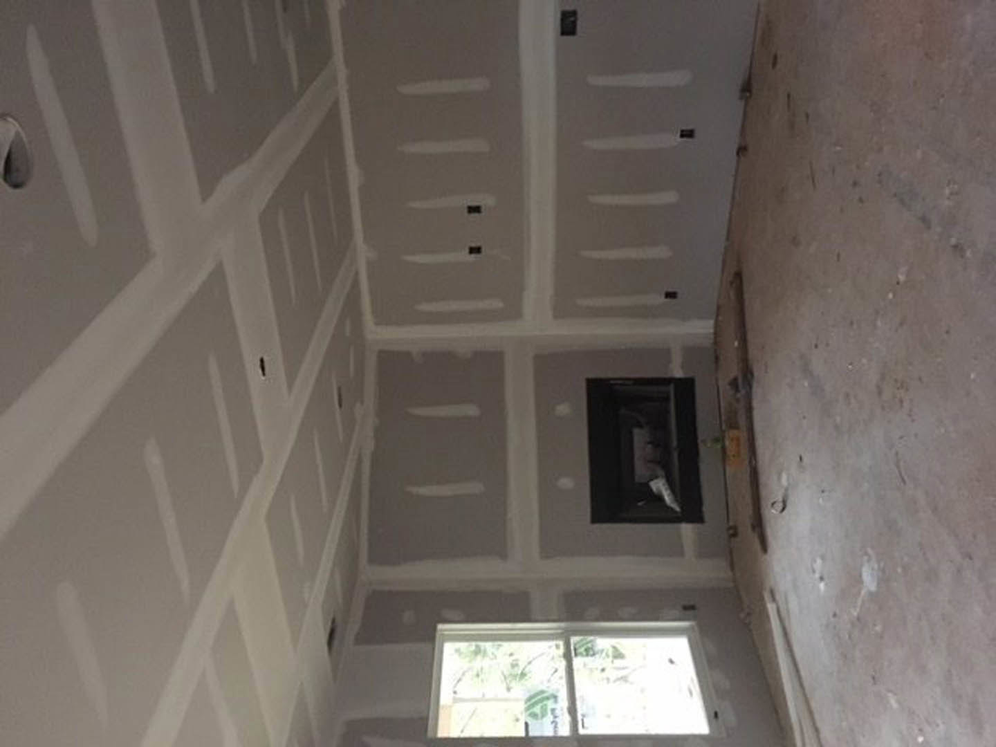 White-walled room featuring a large window with a white frame, plaster walls, ceiling molding, and natural daylight illuminating the interior
