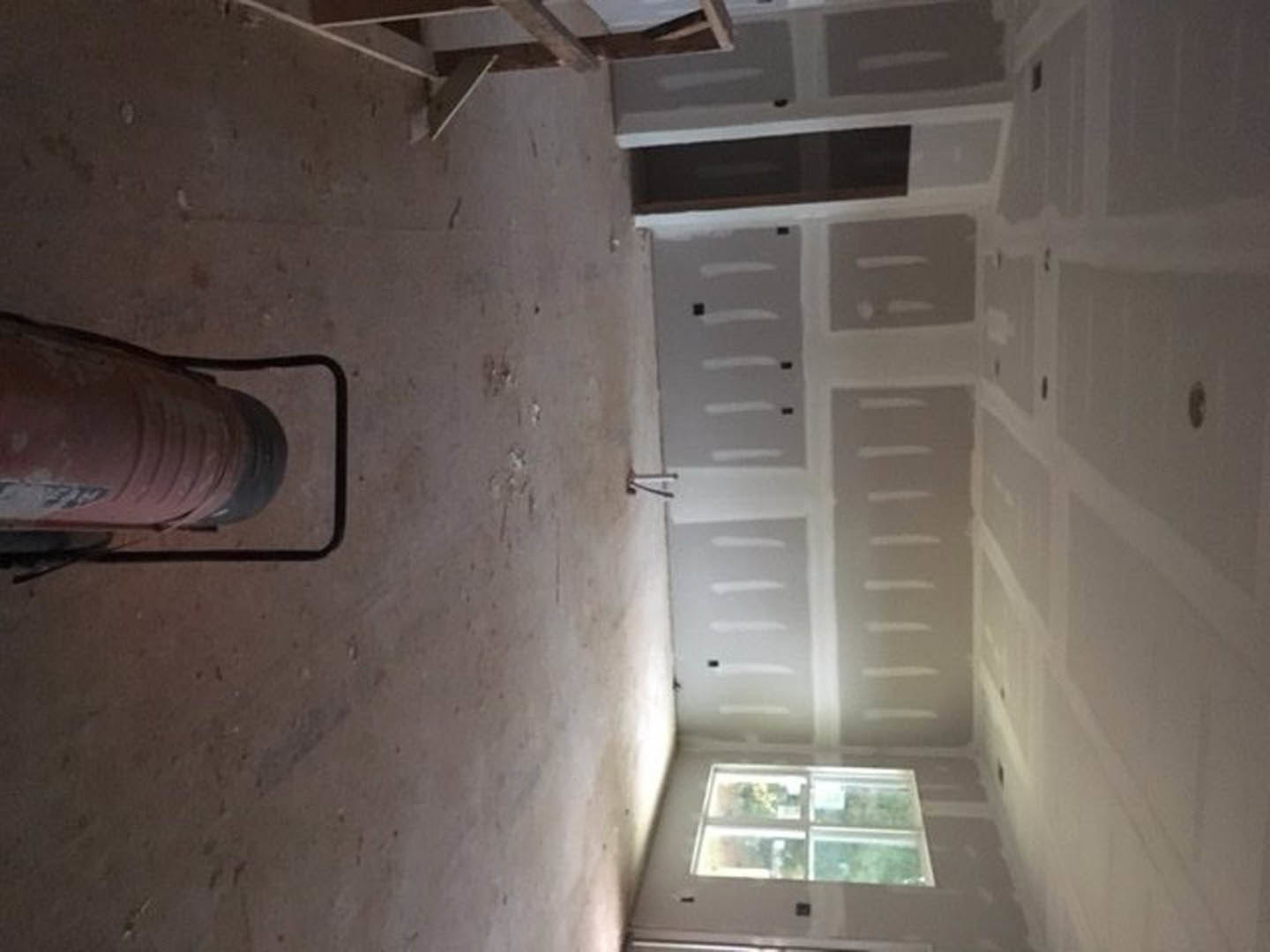 Spacious room with white plaster ceiling, smooth walls, and prominent large cylindrical fixture positioned centrally