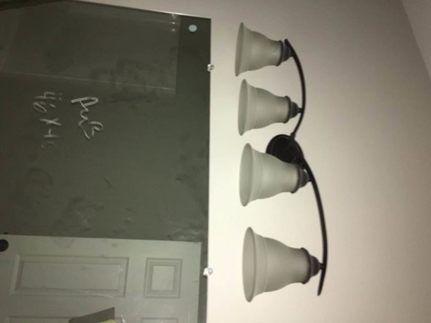 White bell-shaped wall sconce with black cord mounted on smooth interior wall