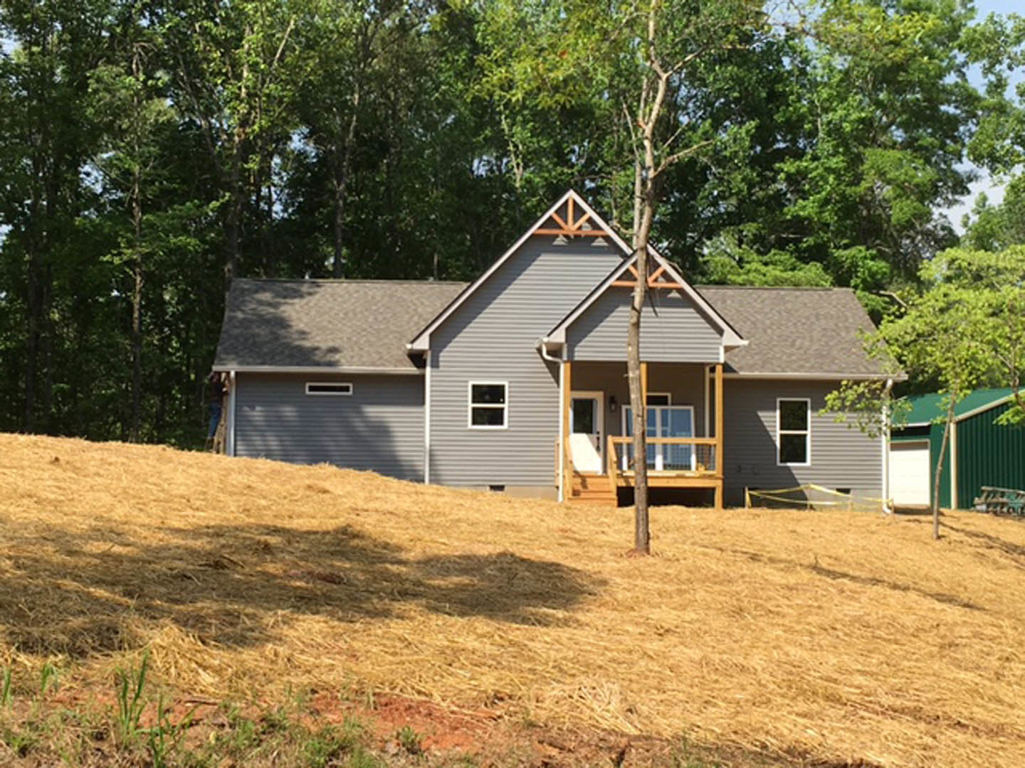 White cottage-style home with a covered porch, fenced yard, large tree in front, grassy lawn, and white-framed windows.