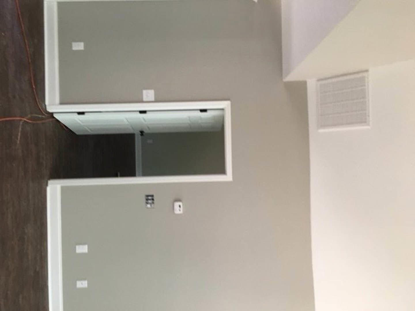 White door set in a neutral-toned room with a white electrical outlet featuring a black logo on the adjacent wall