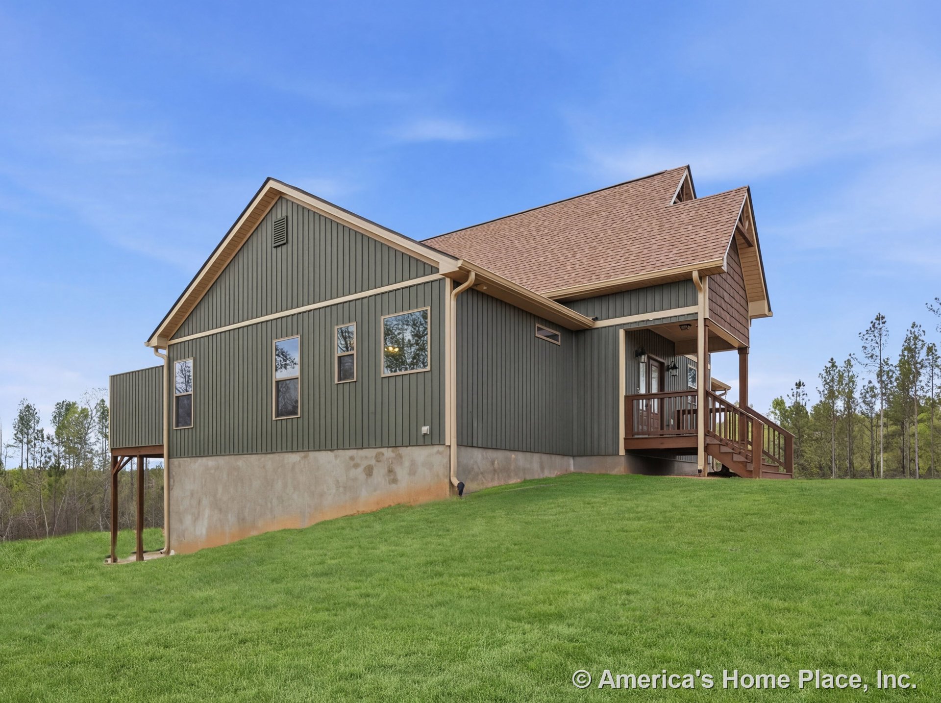 Vertical board siding exterior with covered entry porch, wood railing, multiple rectangular windows, gable roof, concrete foundation, prominent trim, stairs, extended eaves, and