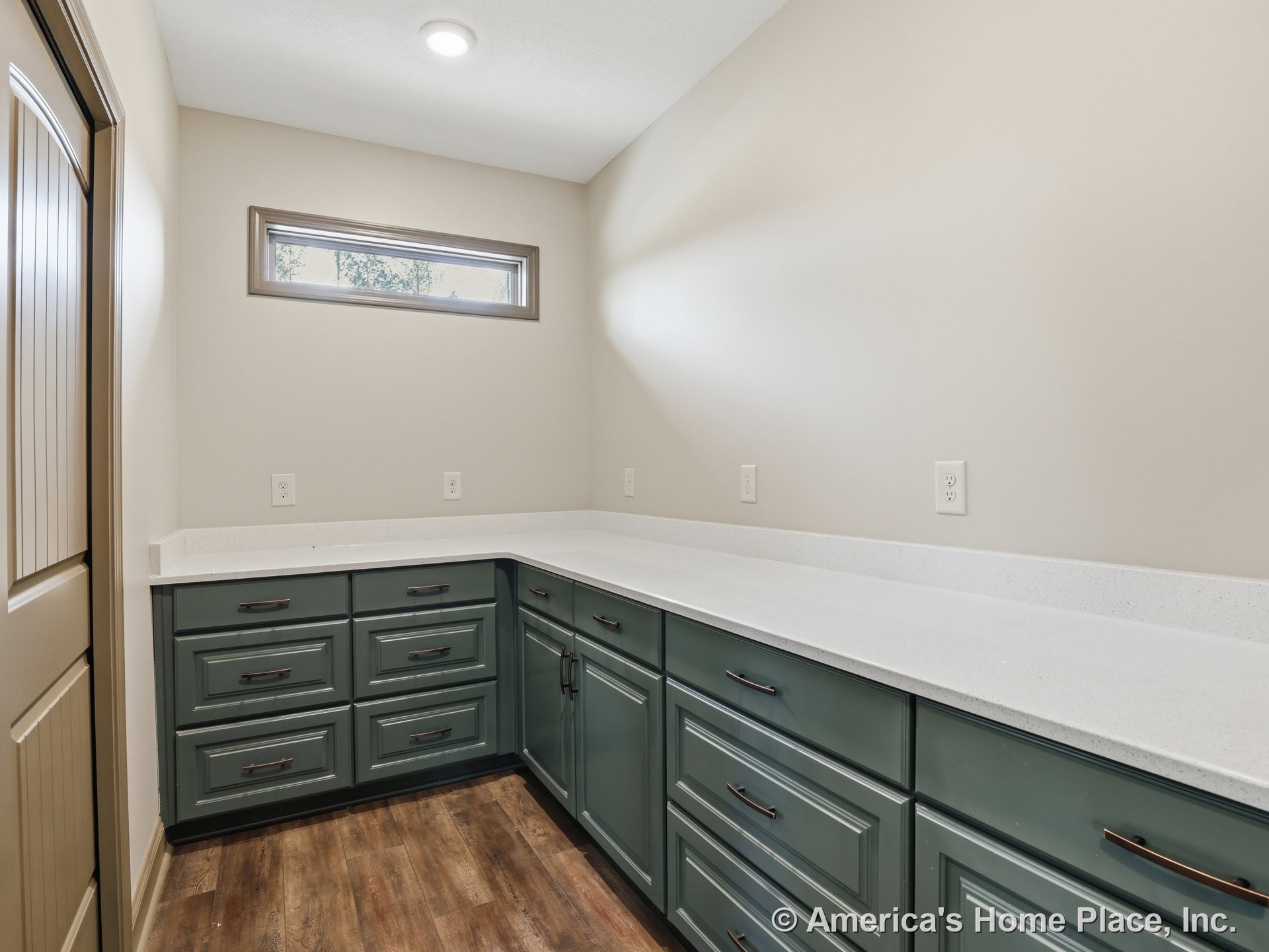 Green built-in cabinetry with brushed metal drawer pulls, white quartz countertops, wood-look flooring, narrow horizontal transom window, recessed ceiling light, multiple
