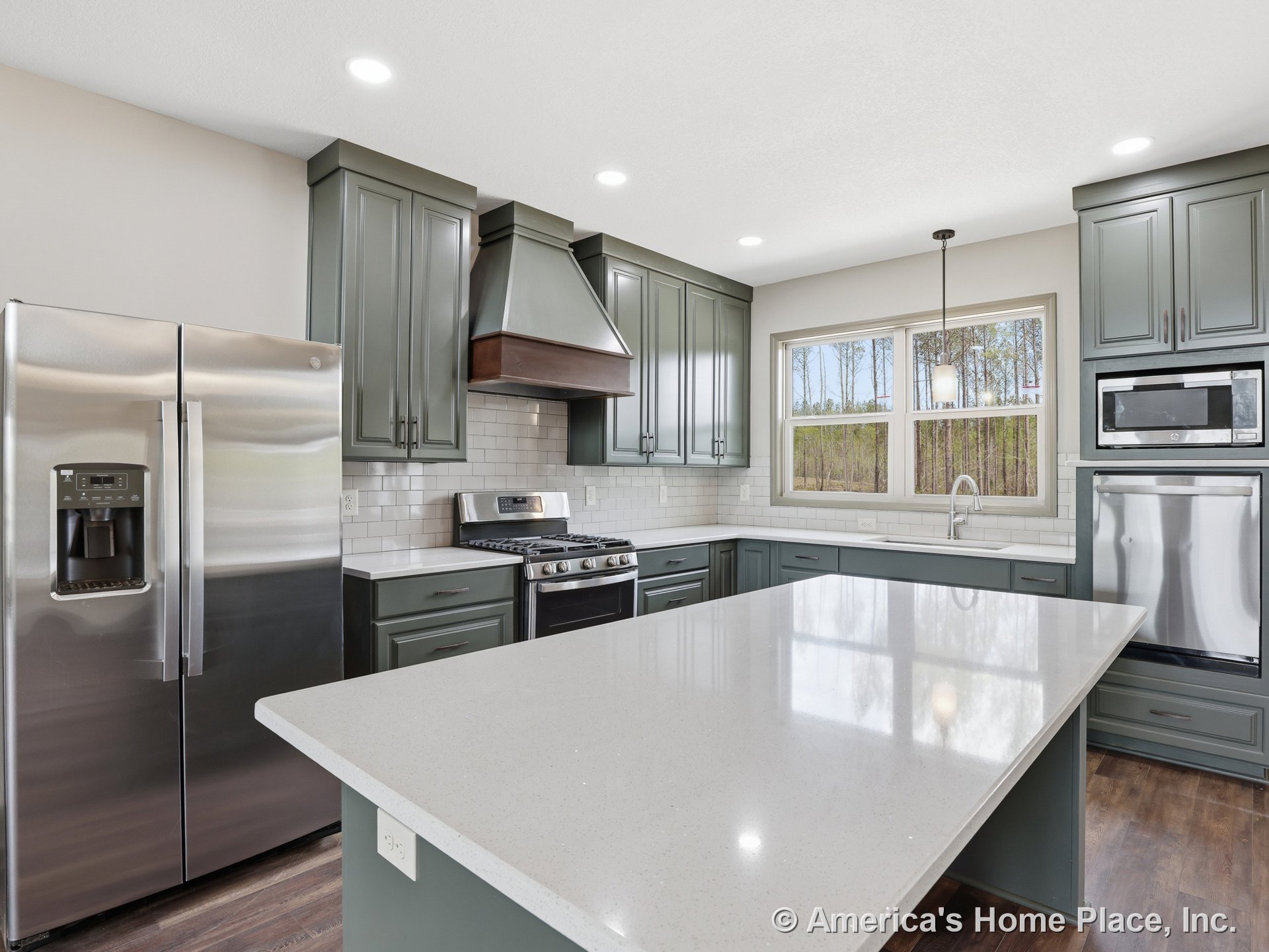 Green shaker cabinets with quartz countertops, subway tile backsplash, large kitchen island, stainless steel refrigerator and gas range, pendant lighting, double window above sink