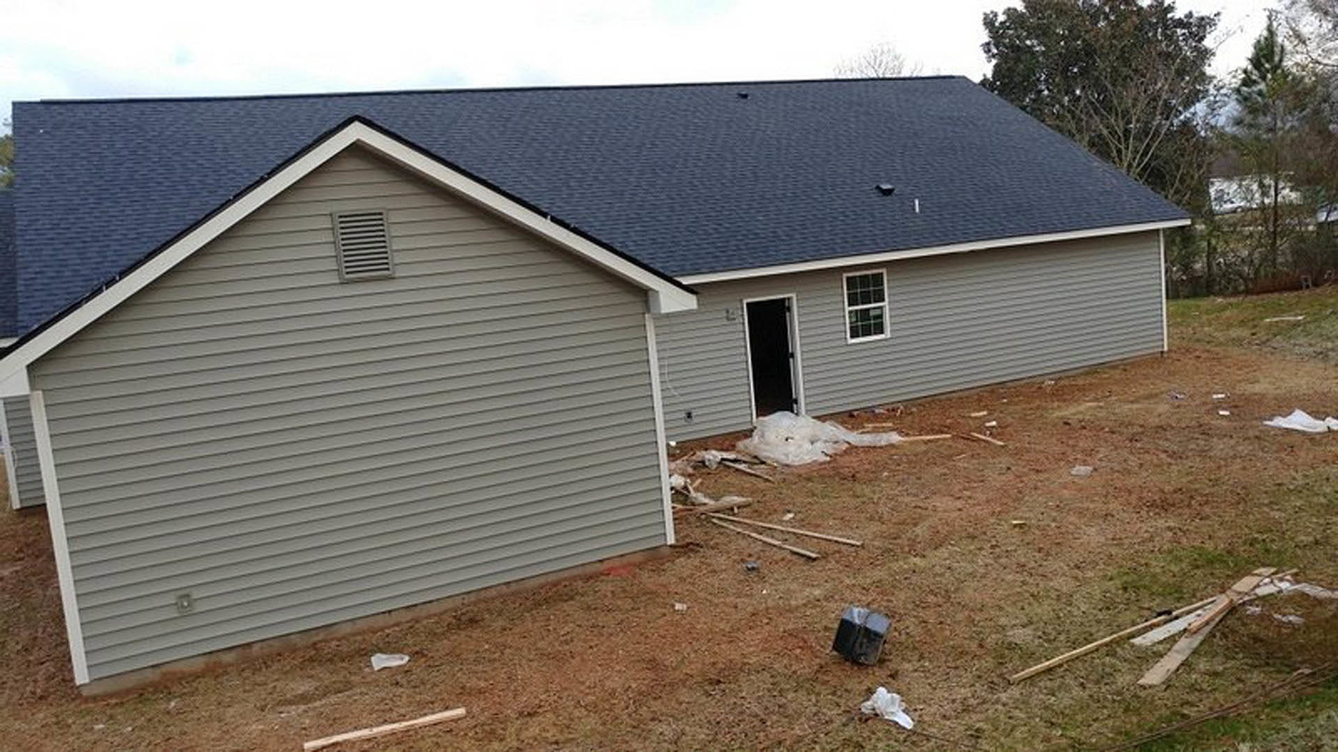Two-story home with gray shingle roof, white siding, multi-pane windows, black front door, attached garage, and exterior wall vent