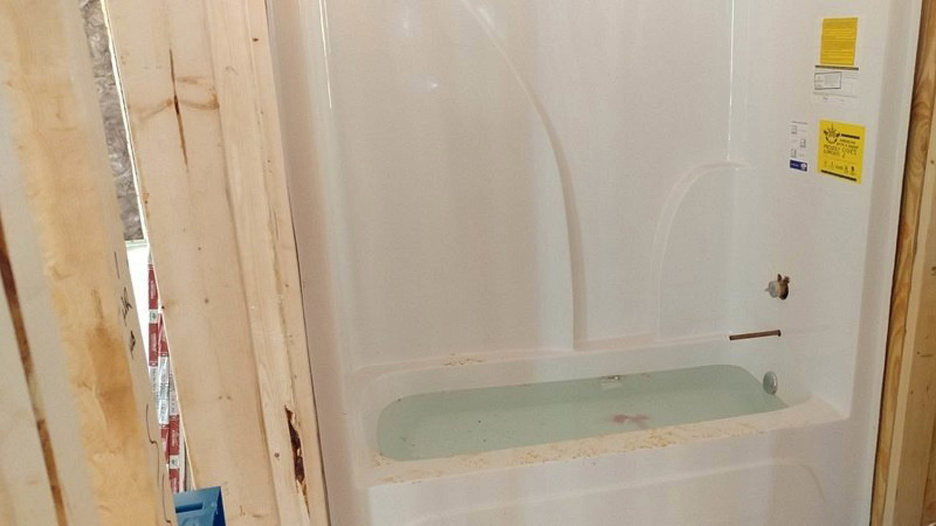 Freestanding white bathtub with chrome faucet against light gray tiled wall in modern bathroom