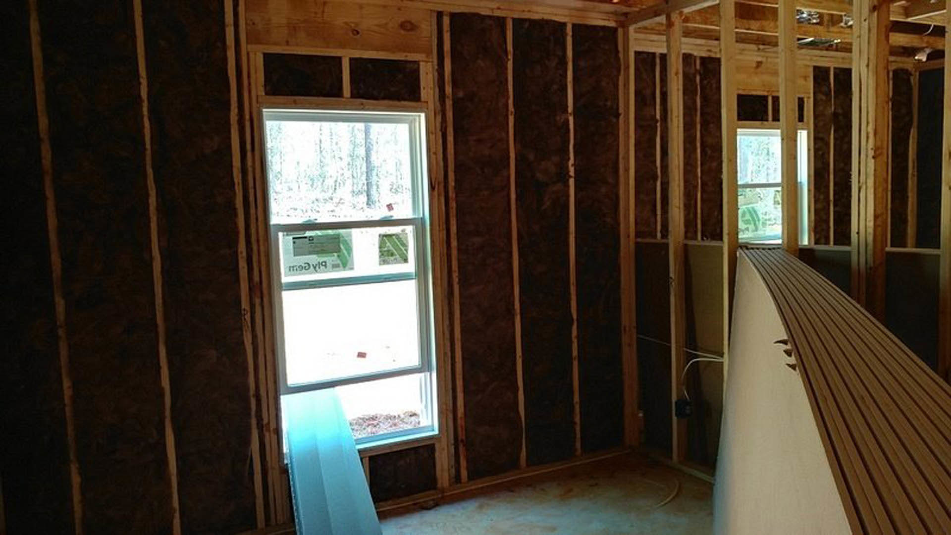 Bright room featuring two large windows with blue curtains, hardwood plank flooring, white carpet, and a wooden board detail.