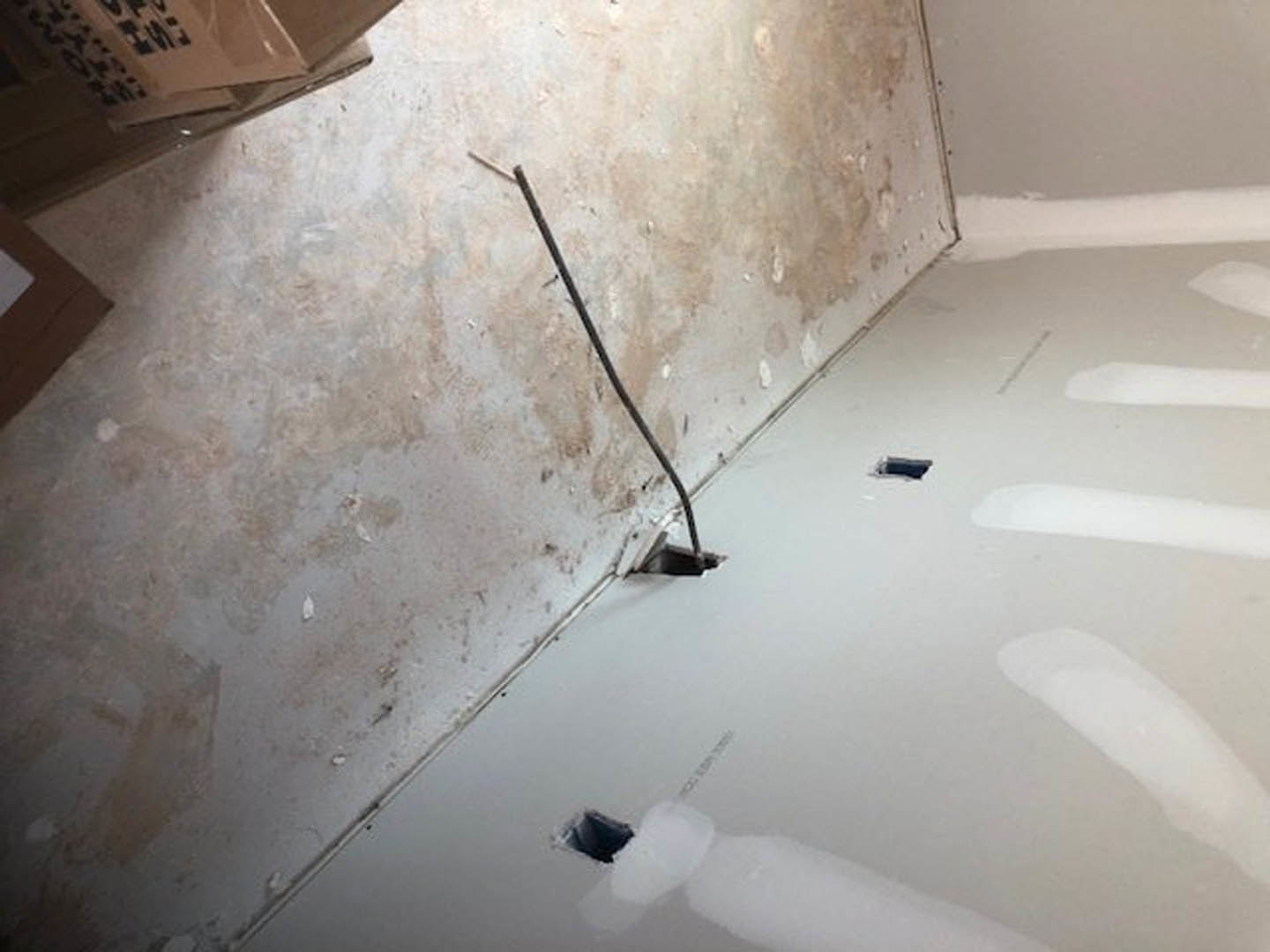 White plaster wall with multiple circular holes, smooth marble floor, recessed ceiling lights, and minimal modern interior finishes.